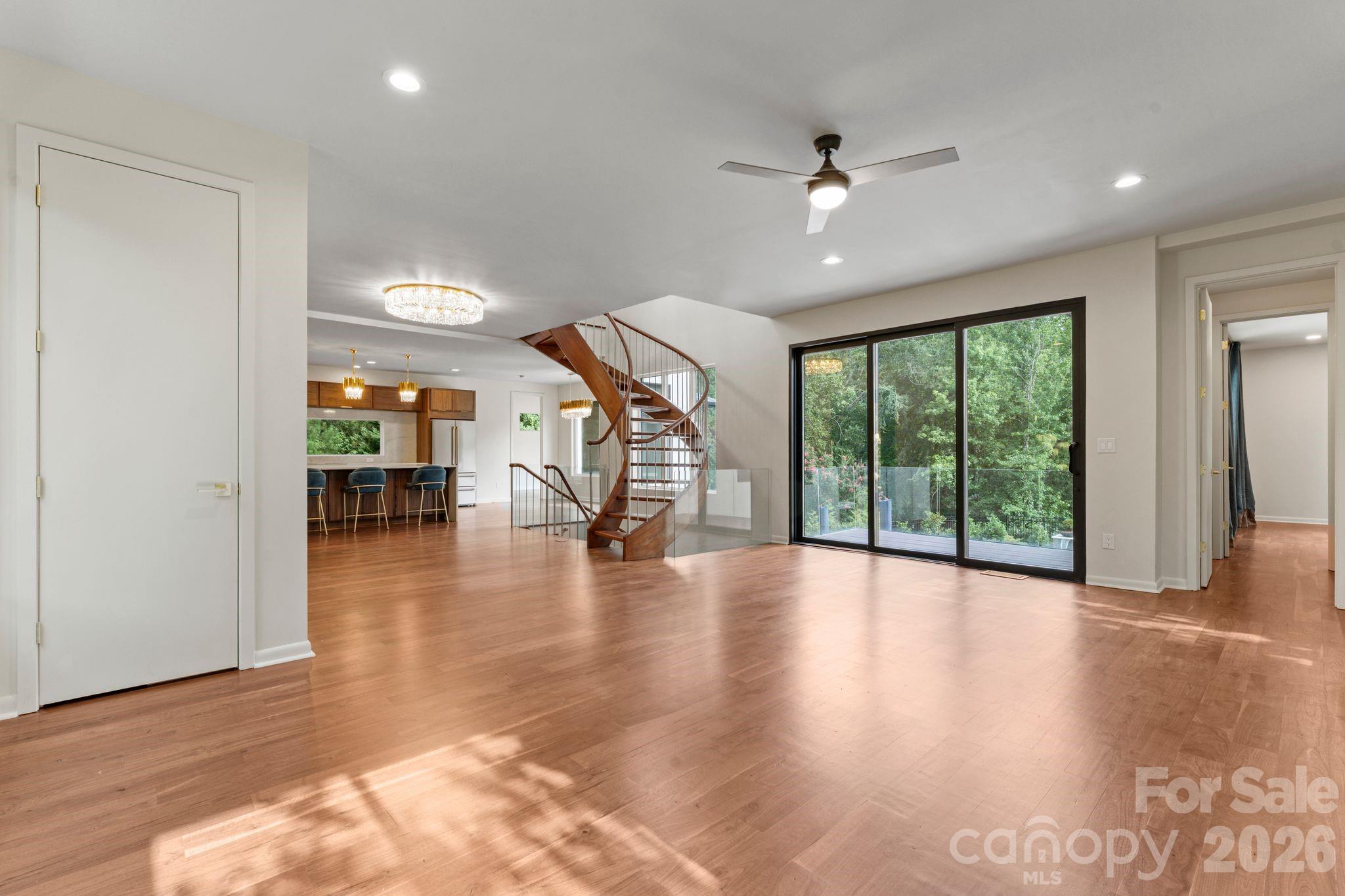 Bright open-concept living room with oak hardwood floors and oversized sliding glass doors overlooking the pool - 1064 Greylyn Drive, Matthews