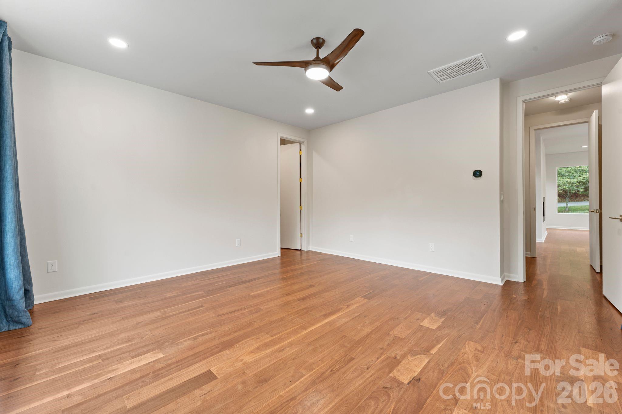 Main floor primary bedroom with walk in closet and pools views. - 1064 Greylyn Drive, Matthews