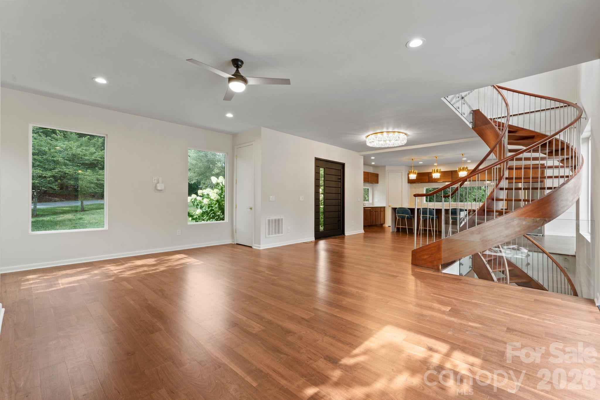 Two-story great room with oak spiral staircase, paneled glass, gas fireplace, and hardwood floors - 1064 Greylyn Drive, Matthews
