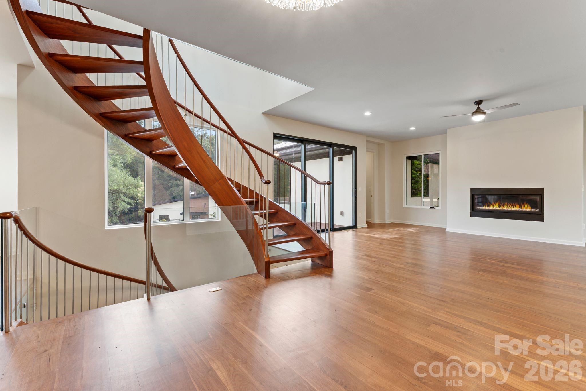 Two-story great room with oak spiral staircase, paneled glass, gas fireplace, and hardwood floors - 1064 Greylyn Drive, Matthews