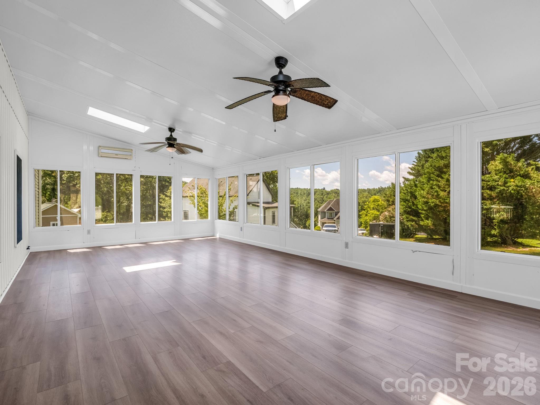 This is the view coming into the sunroom and looking to the left; brand new LVP flooring and a new mini-split has been installed for year-round enjoyment. The sunsets from this West facing room are also breathtaking. - 355 Hidden Meadow Drive, Hendersonville