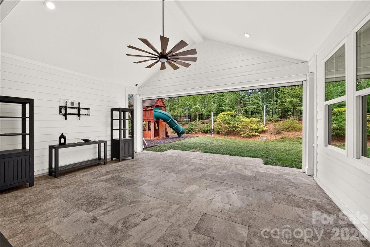 This wonderful porch overlooking a treed back yard with travertine pavers, vaulted ceiling, TV bracket remains the the screen is motorized for bug free entertaining - 3142 Sherman Drive, Lancaster