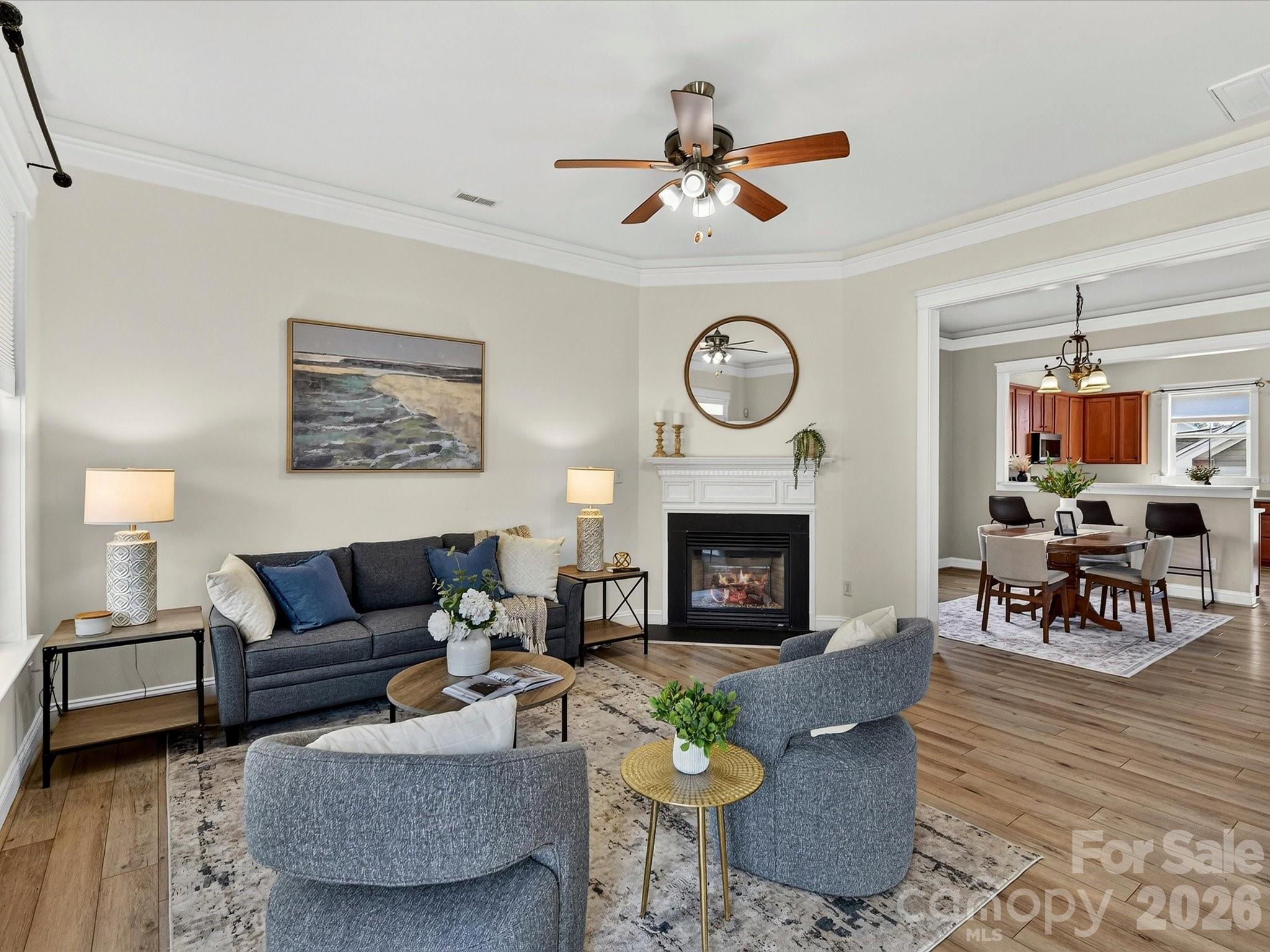 The inviting Great Room features elegant crown molding, a cozy fireplace, abundant natural light, and an open layout that flows seamlessly into the dining area and kitchen. - 13106 Kennerly Drive, Huntersville