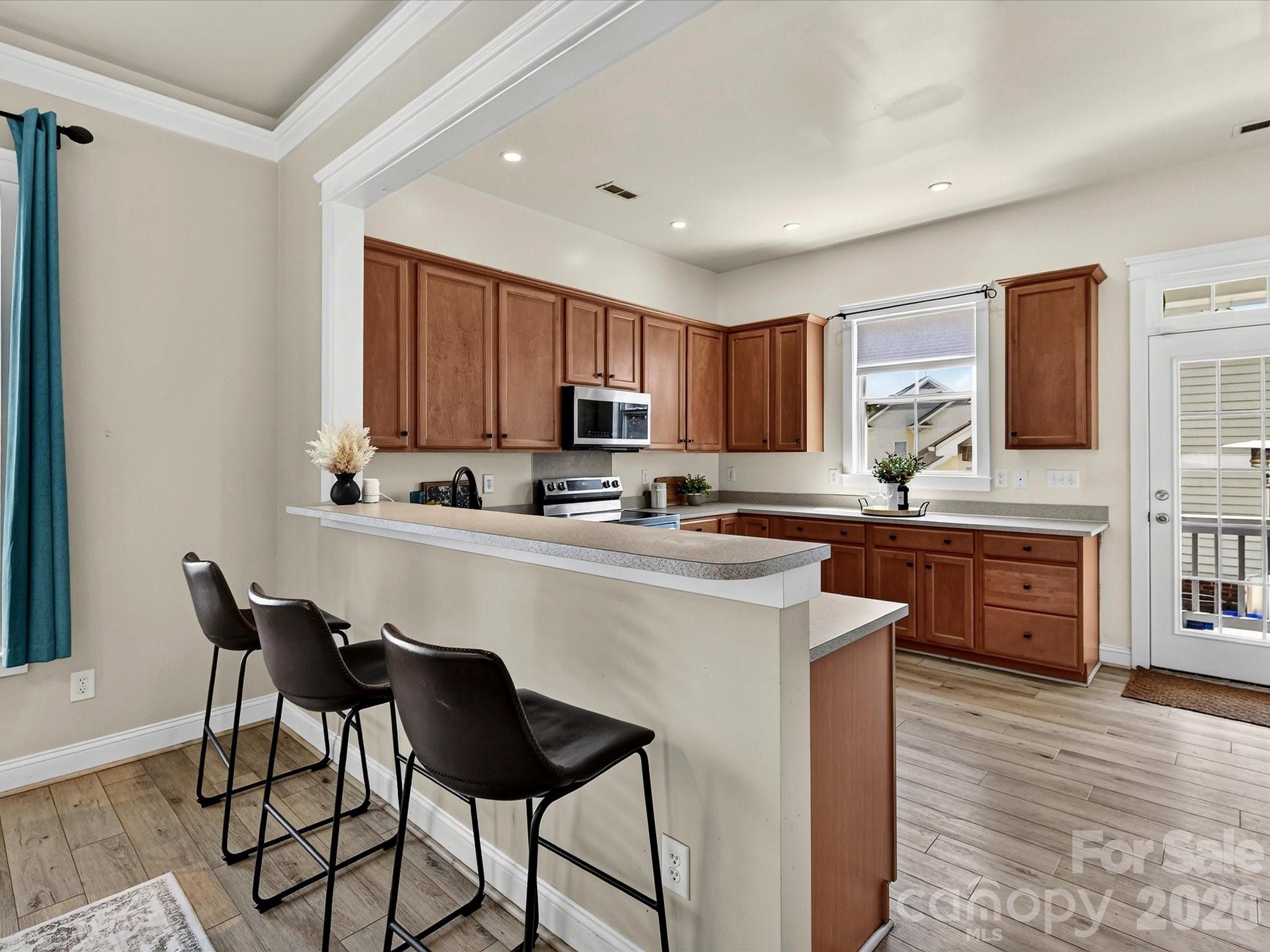 The thoughtfully designed kitchen showcases generous cabinet storage, plentiful prep space, stainless steel appliances, and a convenient breakfast bar overlooking the open-concept living spaces. - 13106 Kennerly Drive, Huntersville