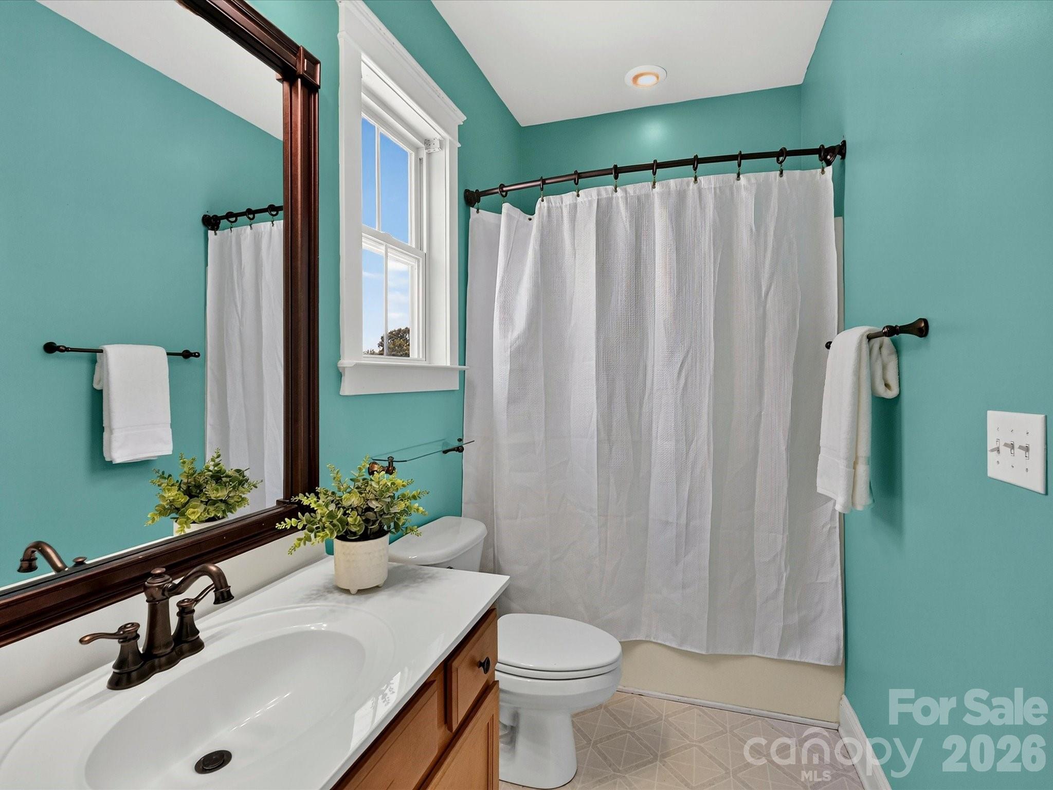 The well-appointed full bath features a spacious vanity, a tub/shower combination, and a window that fills the space with natural light. - 13106 Kennerly Drive, Huntersville