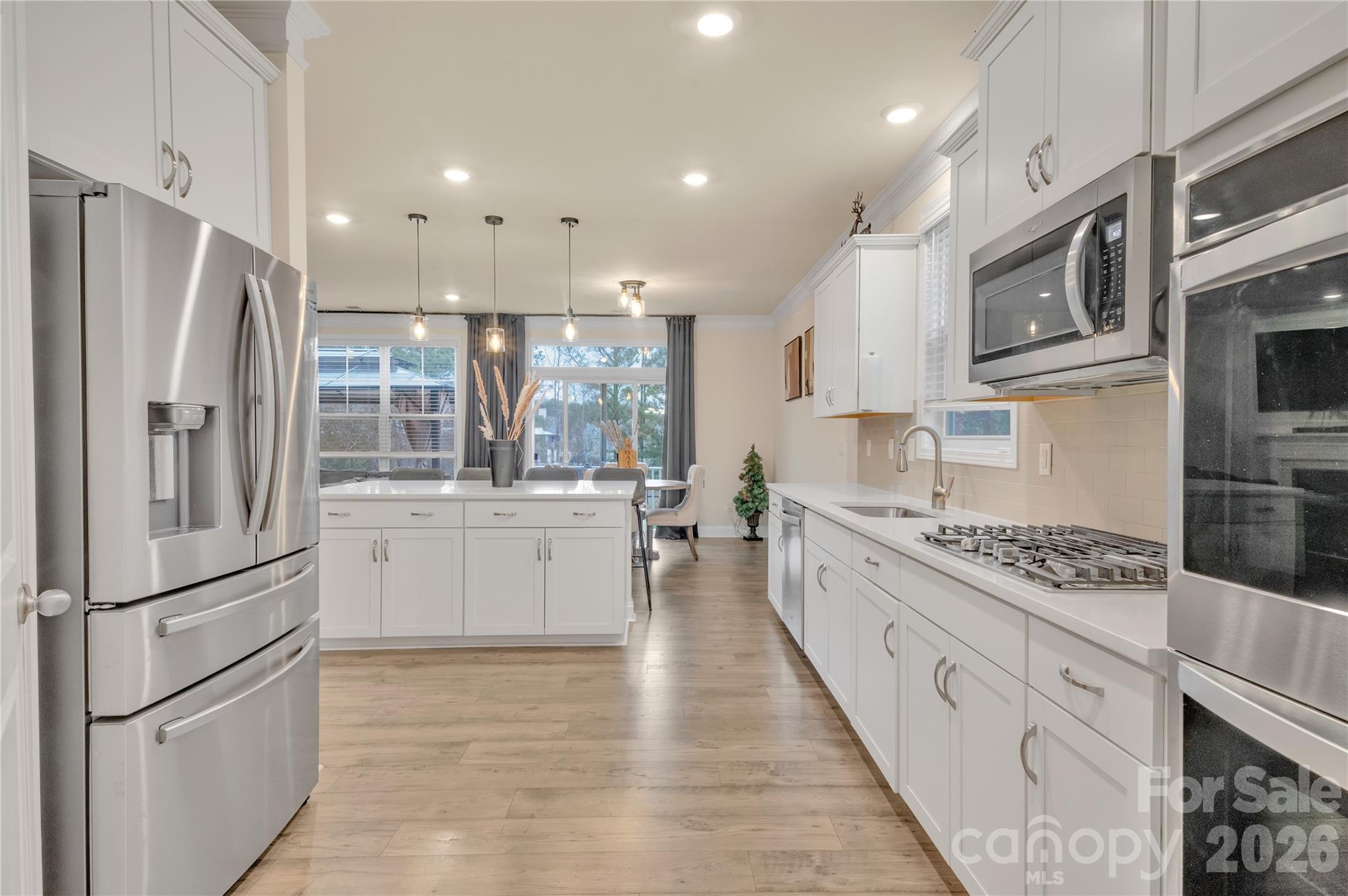 A chefs dream, this stunning gourmet kitchen features white shaker cabinetry, pristine quartz countertops, and premium stainless steel appliances- including a gas cooktop and double wall oven. - 4849 Tacoma Drive, Fort Mill