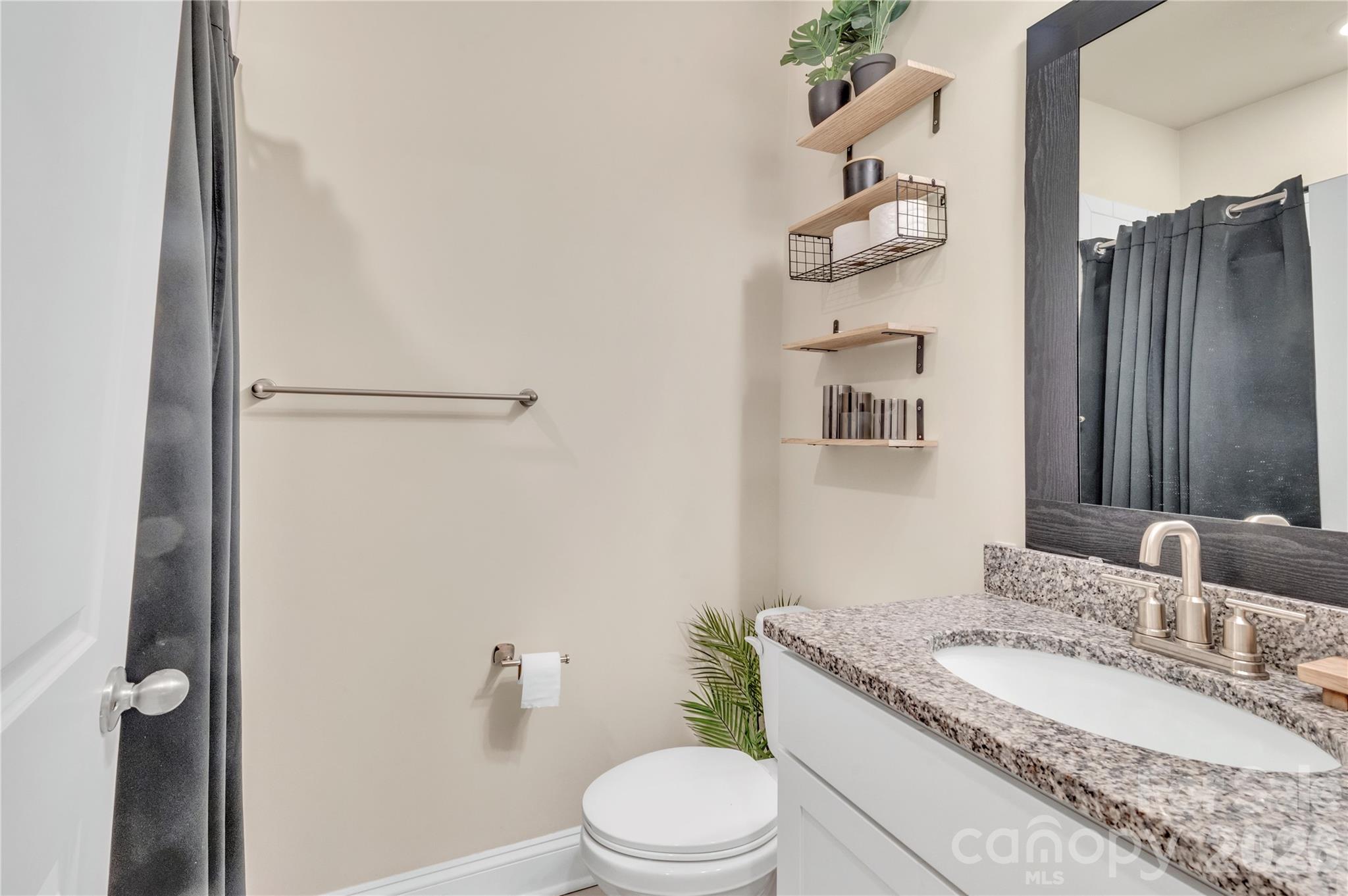 Tucked right next to the main-level guest room, this full bathroom provides effortless accessibility for friends and family. The space boasts a beautiful granite-topped vanity, brushed nickel hardware, and a crisp, neutral color palette that seamlessly complements the home's overall design - 4849 Tacoma Drive, Fort Mill