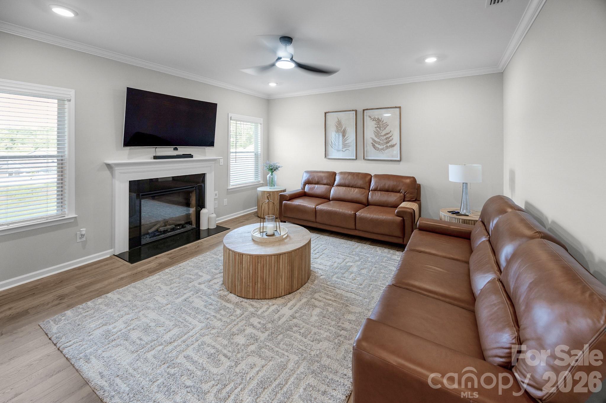 living room opens up from the kitchen area with plenty of natural light and a cozy fireplace - 5080 Mooreland Oaks Way, Mount Holly