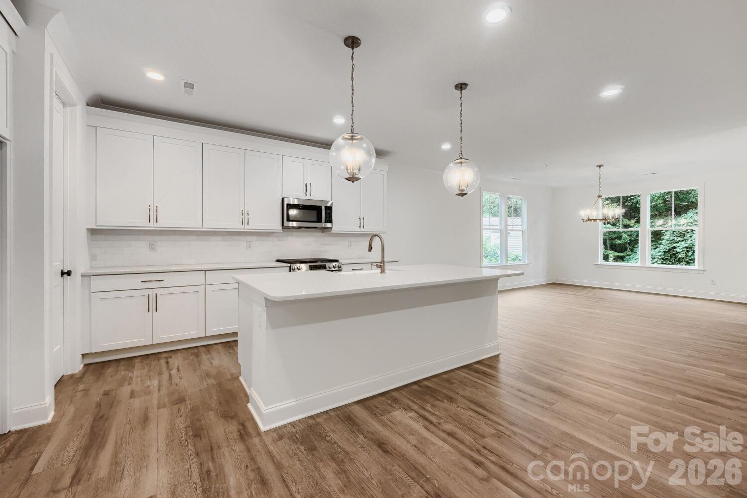 This expansive open floor plan connects the kitchen, dining, and living areas with beautiful wood-look flooring throughout. Recessed lighting and designer pendants keep the whole space bright and inviting. - 2358 Fay Jones Road, Denver