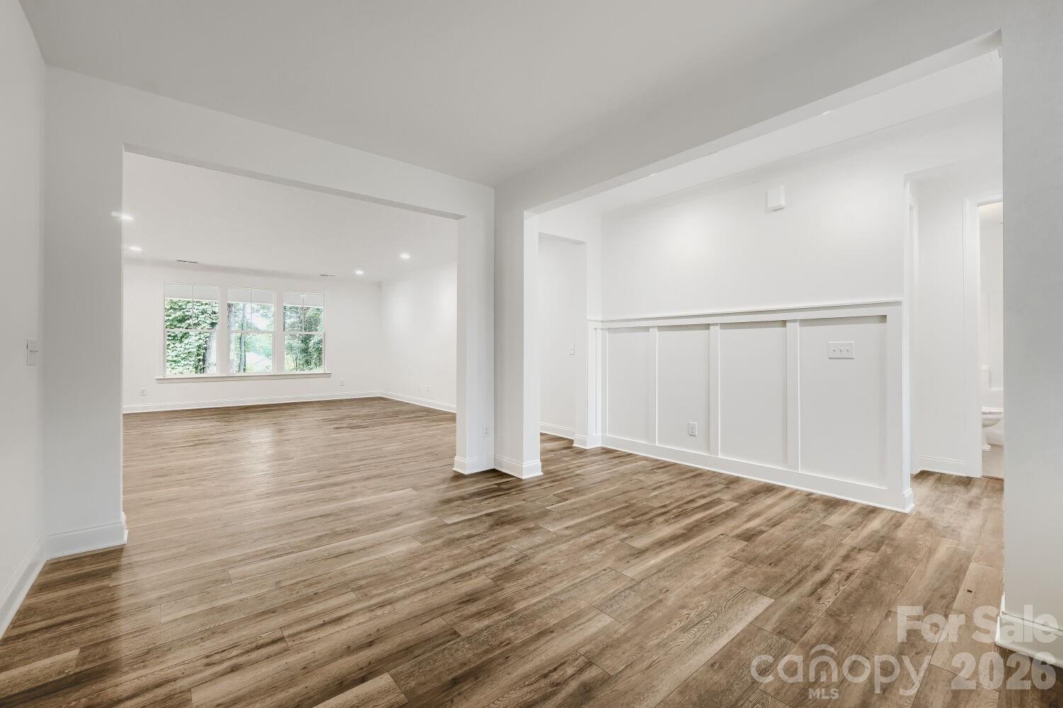 A welcoming entry flows into the open living space with warm wood-look floors and board-and-batten accent detailing. Large windows fill the room with natural light. - 2358 Fay Jones Road, Denver