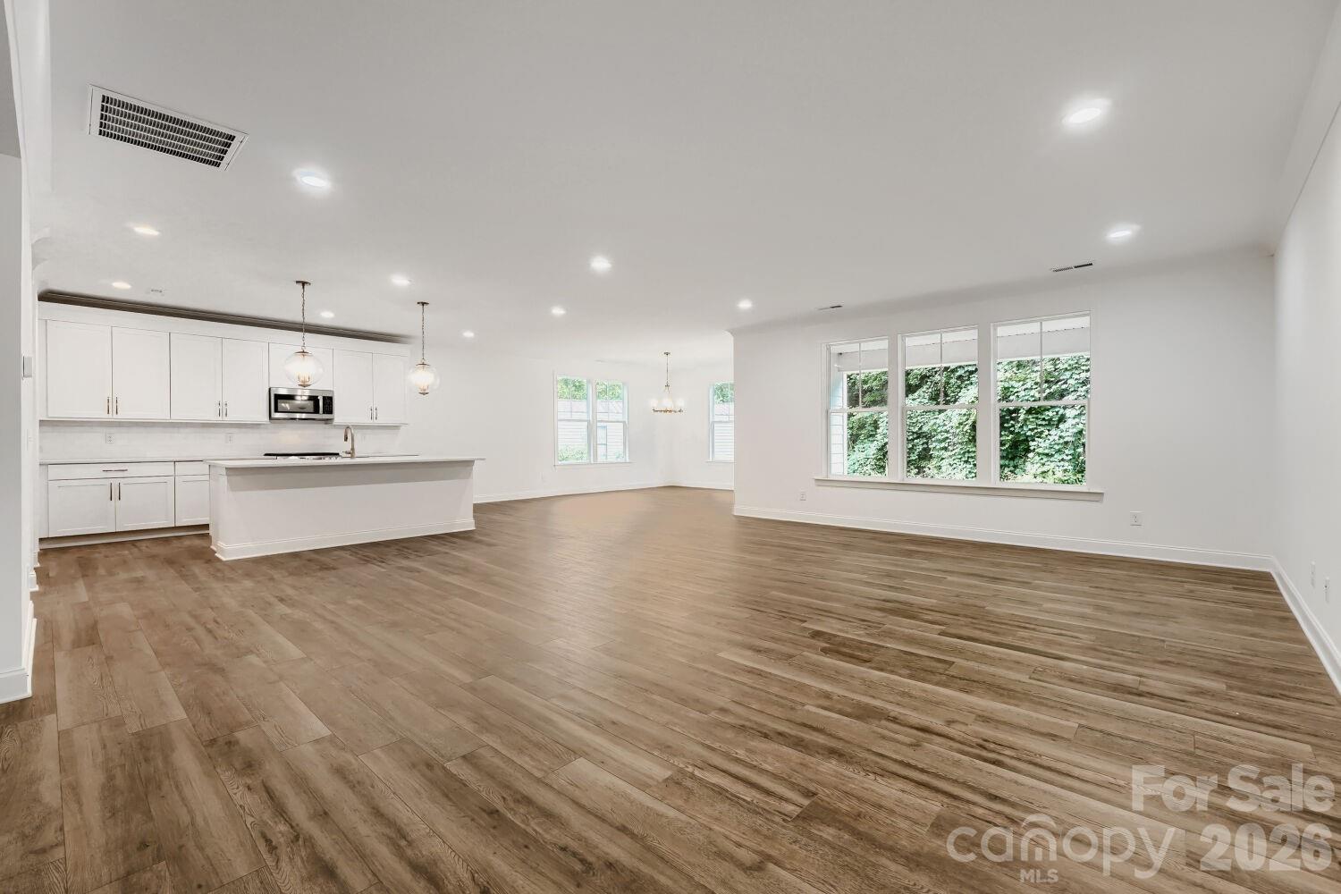 A bright, open-concept living area with rich wood-look flooring and elegant wainscoting. Wide entryways connect the space effortlessly to the rest of the home. - 2358 Fay Jones Road, Denver