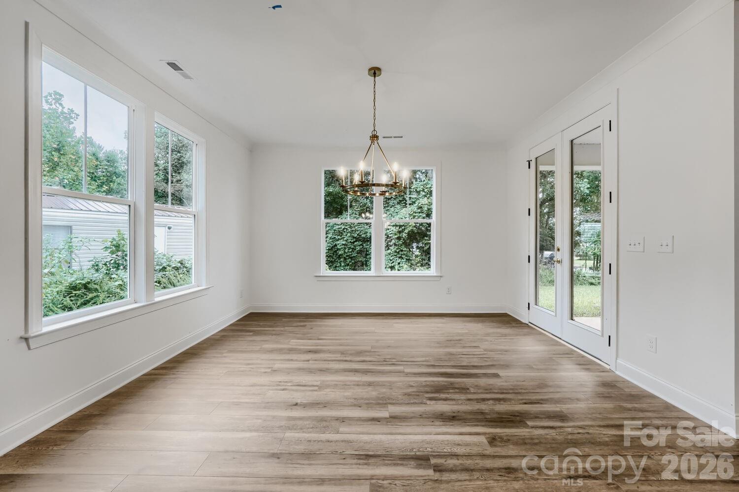 A charming dining space anchored by an elegant chandelier and framed by windows on two sides. French doors open directly to the backyard for indoor-outdoor living. - 2358 Fay Jones Road, Denver