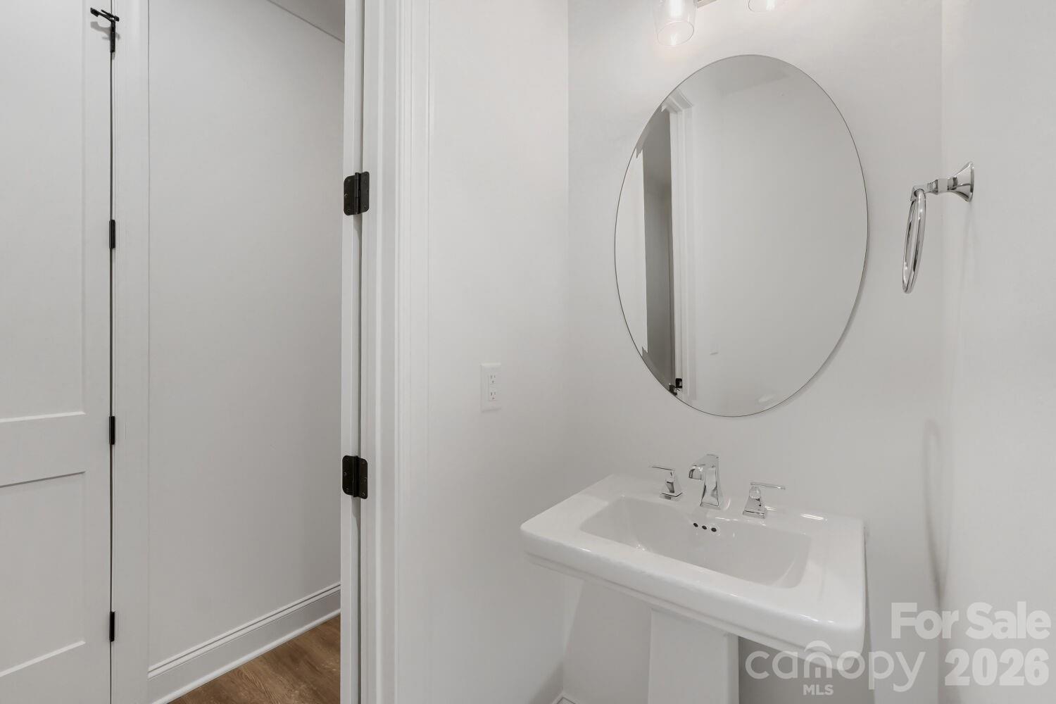 This tucked-away powder room keeps things simple with a pedestal sink and a stylish round mirror. Chrome fixtures and fresh white walls give it a clean, elegant touch. - 2358 Fay Jones Road, Denver