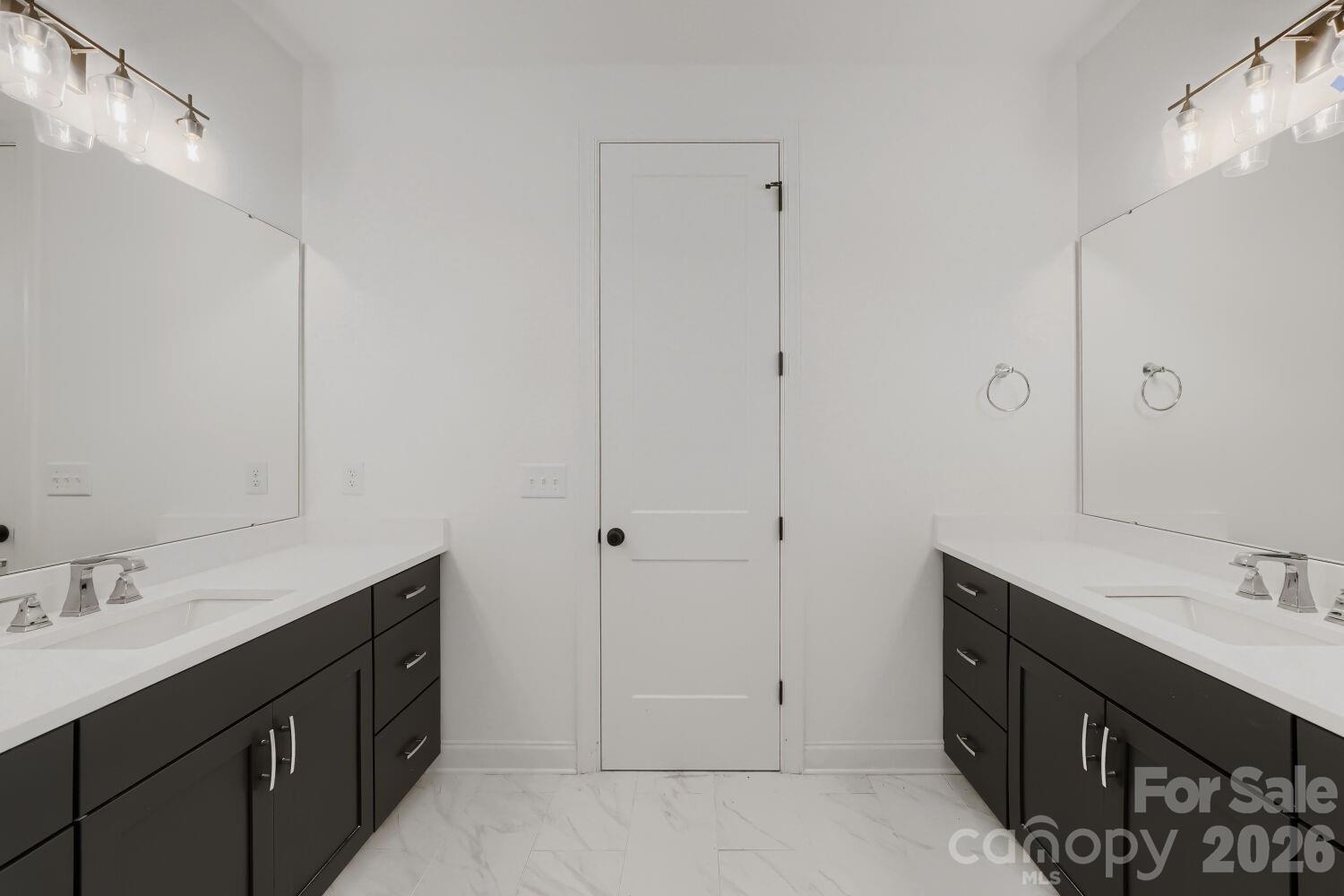 Double vanities anchor each side of this bright primary bathroom. Marble-look tile flooring and a central linen closet deliver both style and storage. - 2358 Fay Jones Road, Denver