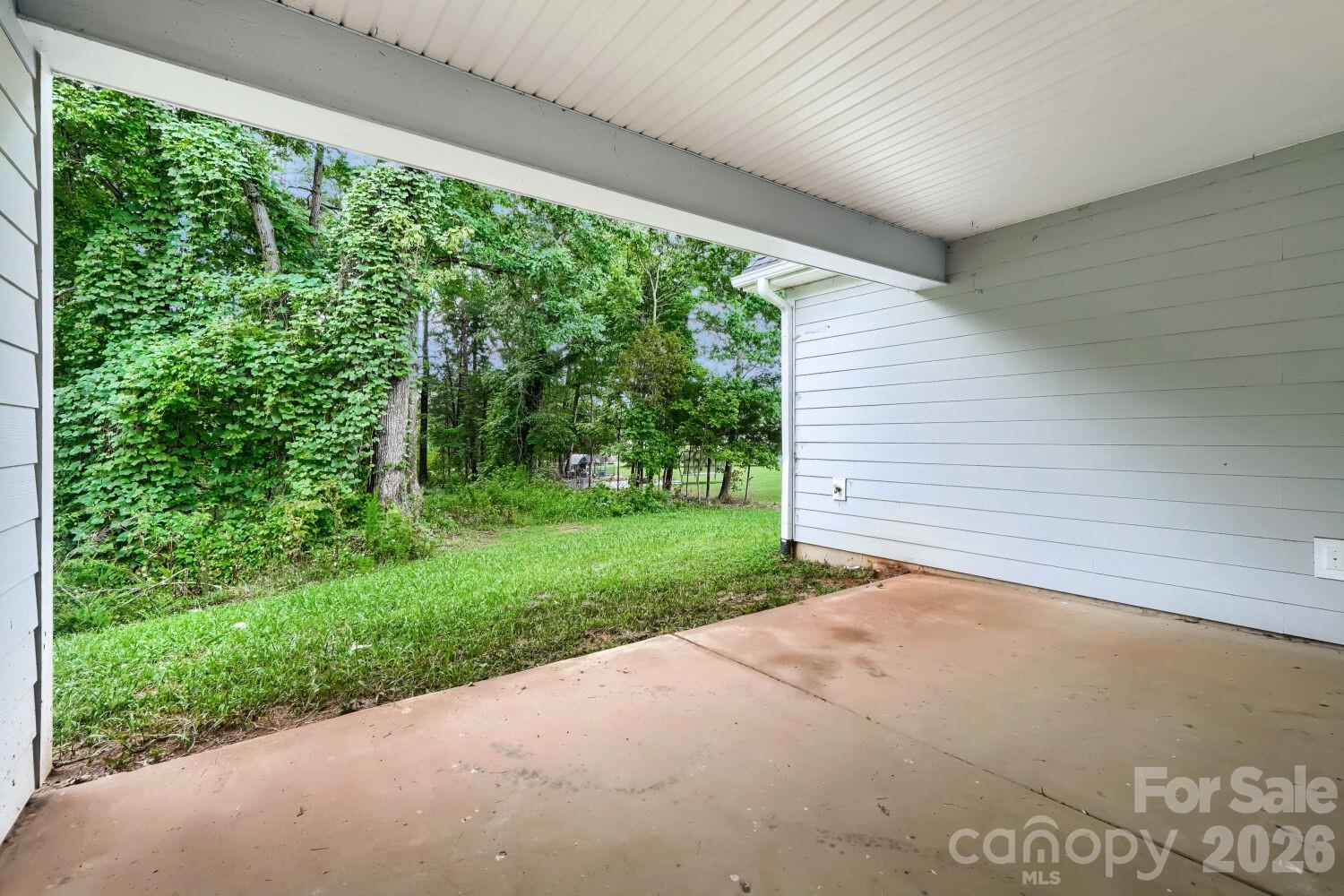 A covered back patio offering a shaded spot to relax and take in the wooded surroundings. The lush, private backdrop is perfect for outdoor enjoyment. - 2358 Fay Jones Road, Denver