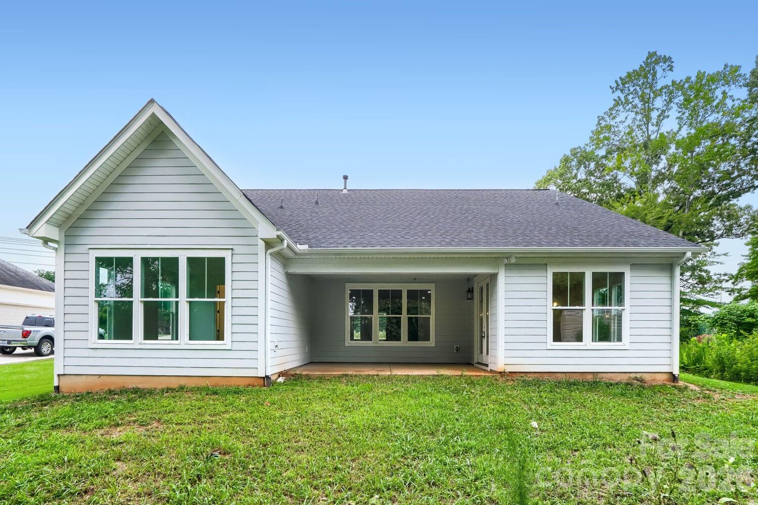 The backyard elevation features a covered patio flanked by large windows and a spacious grassy yard. It's an inviting setup for outdoor gatherings and relaxation. - 2358 Fay Jones Road, Denver