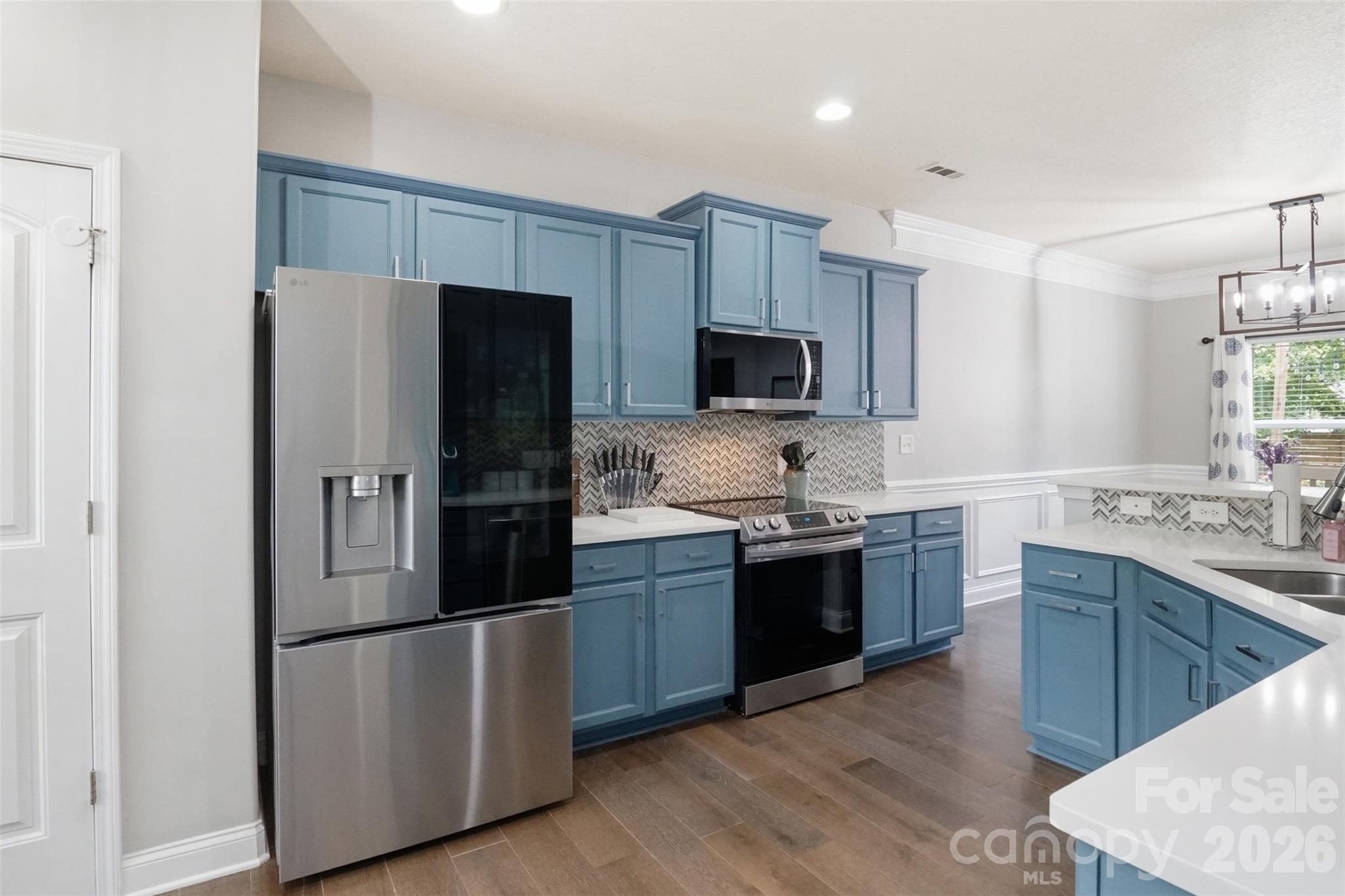 Kitchen with custom backsplash, custom painted cabinets and white quartz! Pantry has double doors for plenty of storage and easy access! - 835 Estuary Court, Rock Hill