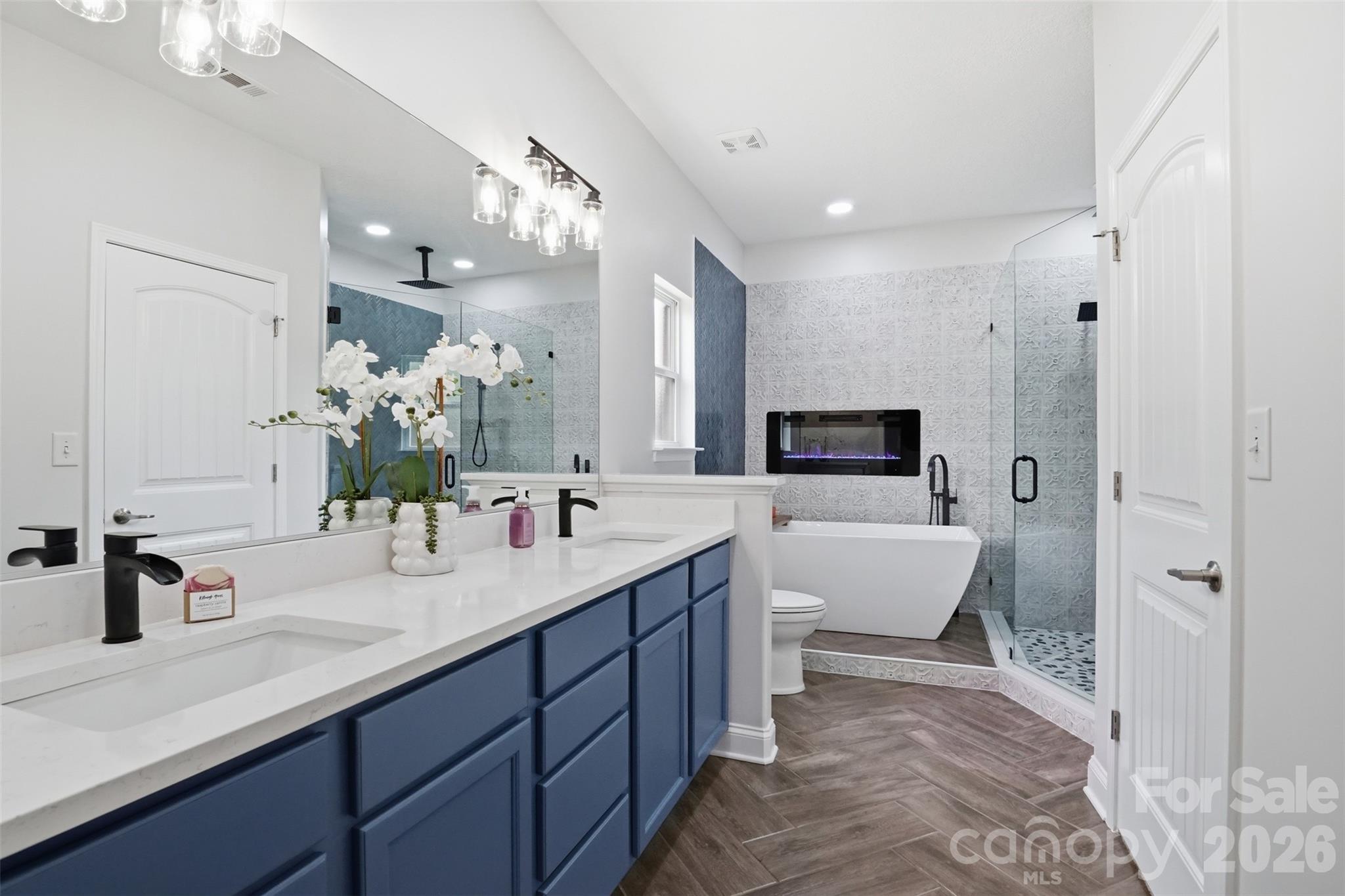 Remodeled primary bath with dual sink vanity, modern soaking tub, wall electric fireplace with heat and/or ambiance features and separate primary shower! Walk-in custom closet to the right! - 835 Estuary Court, Rock Hill