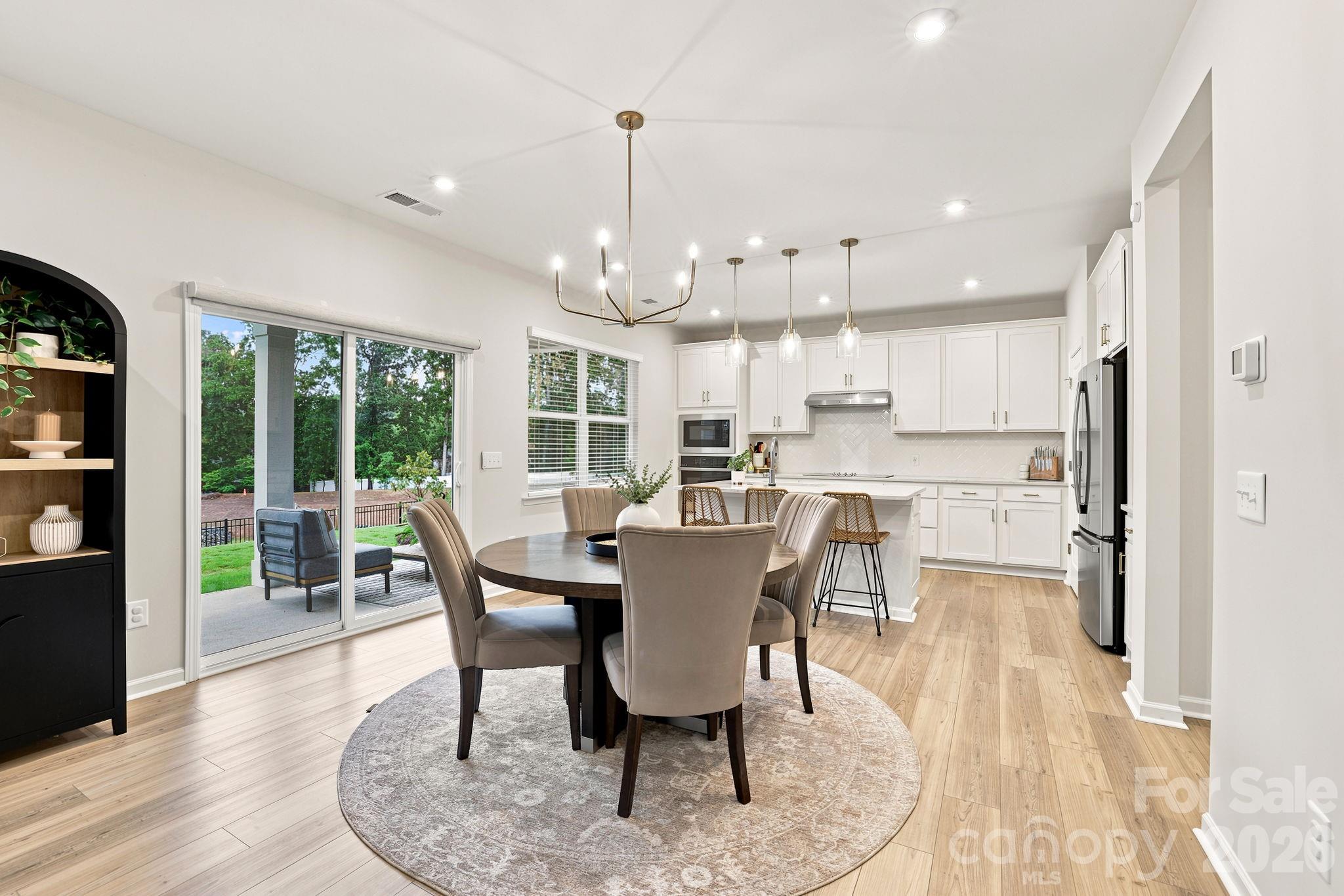 Dining table conveniently located between the Kitchen and Family Room- all with LVP flooring and lots of natural light streaming in. Eaasy access to covered oversized patio! - 8226 Franklin Trail Street, Mint Hill