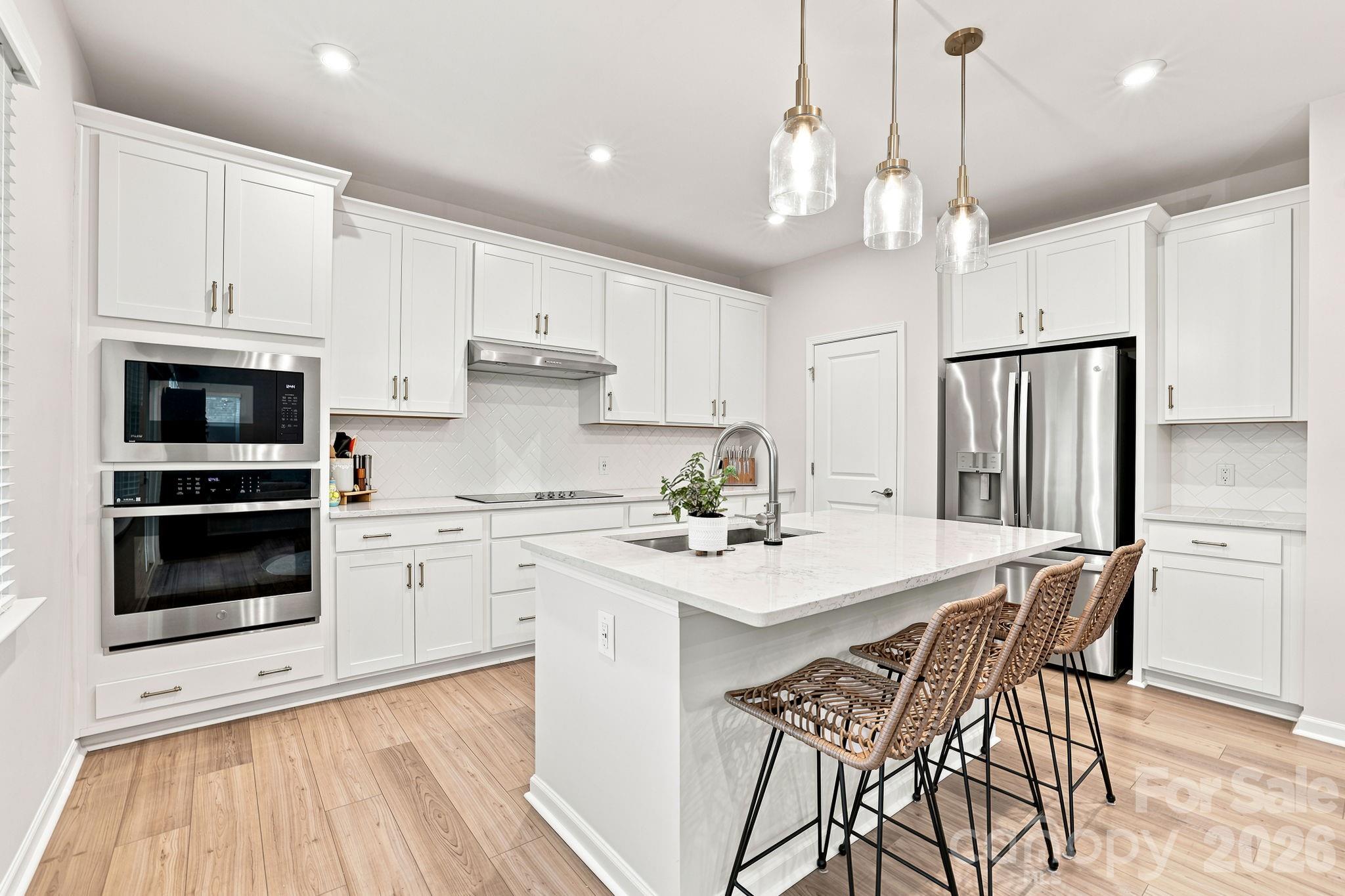 White kitchen with quartz counters, walk-in pantry and lots of recessed lighting - 8226 Franklin Trail Street, Mint Hill