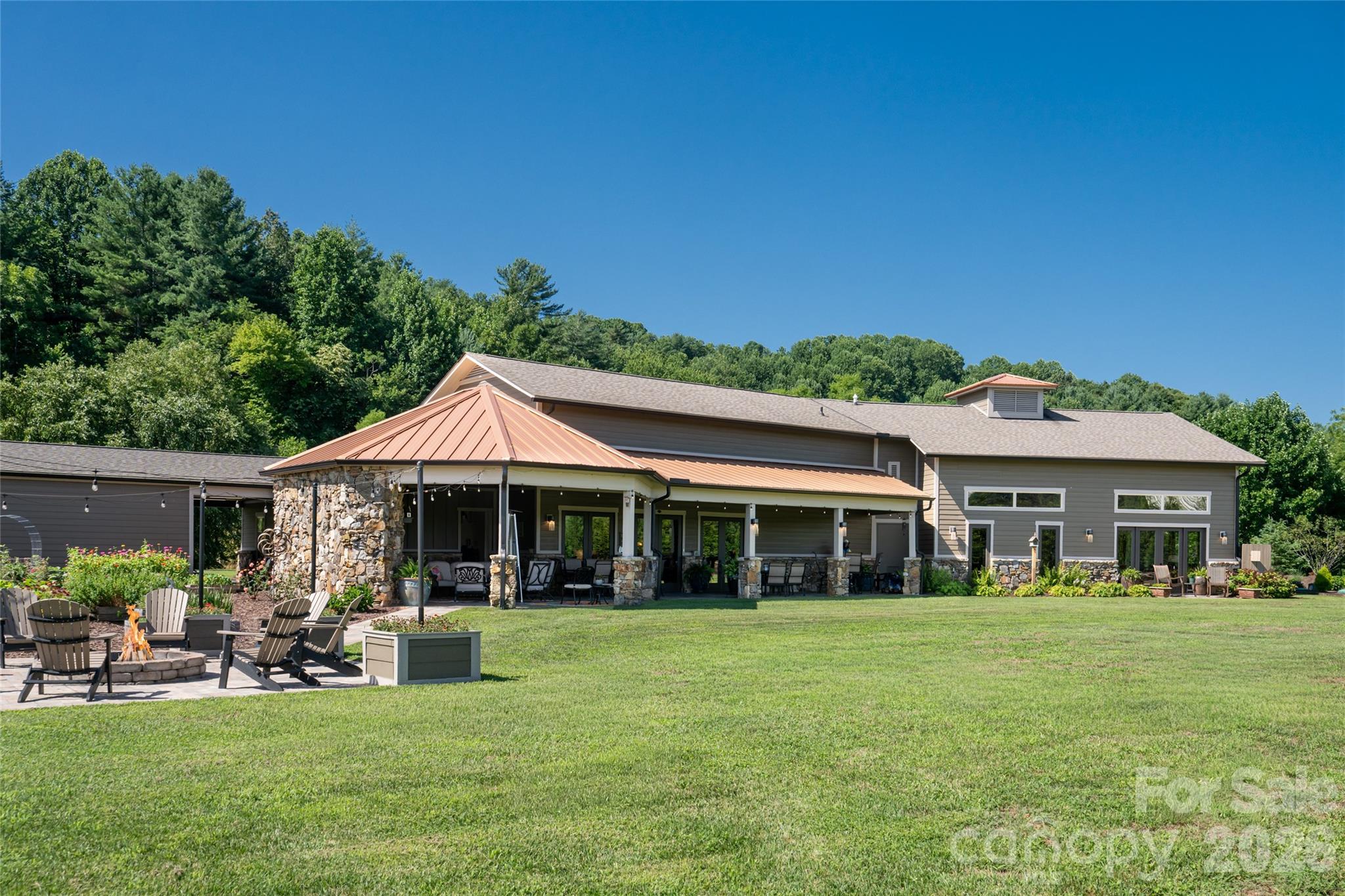 Back side of home with firepit and large covered entertaining patio. - 660 Pleasant Grove Road, Hendersonville