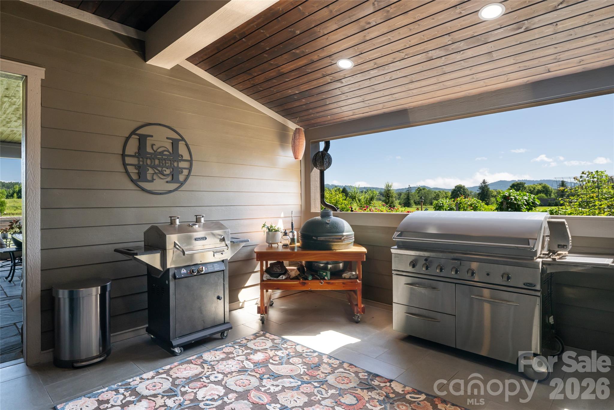 Outdoor grilling area with room for multiple smokers and grills overlooking raised bed garden. - 660 Pleasant Grove Road, Hendersonville