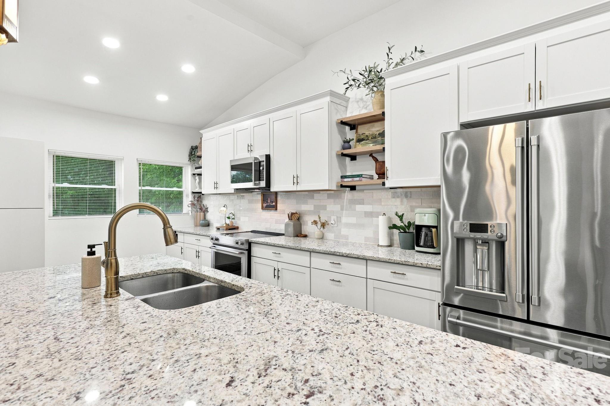 The Kitchen features a large island, plenty of counter space, tile backsplash and wooden shelving for colorful dishes, plants or accessories - 527 S 2nd Street, Albemarle