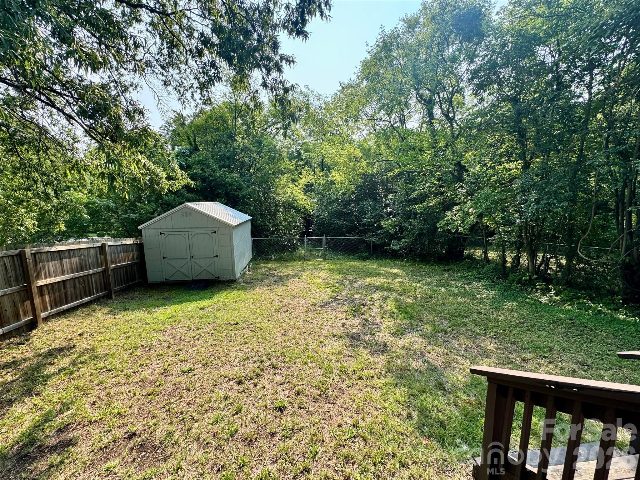 Fenced backyard with storage building. The property goes back beyond the fencing. - 205 Tournament Drive SW, Concord