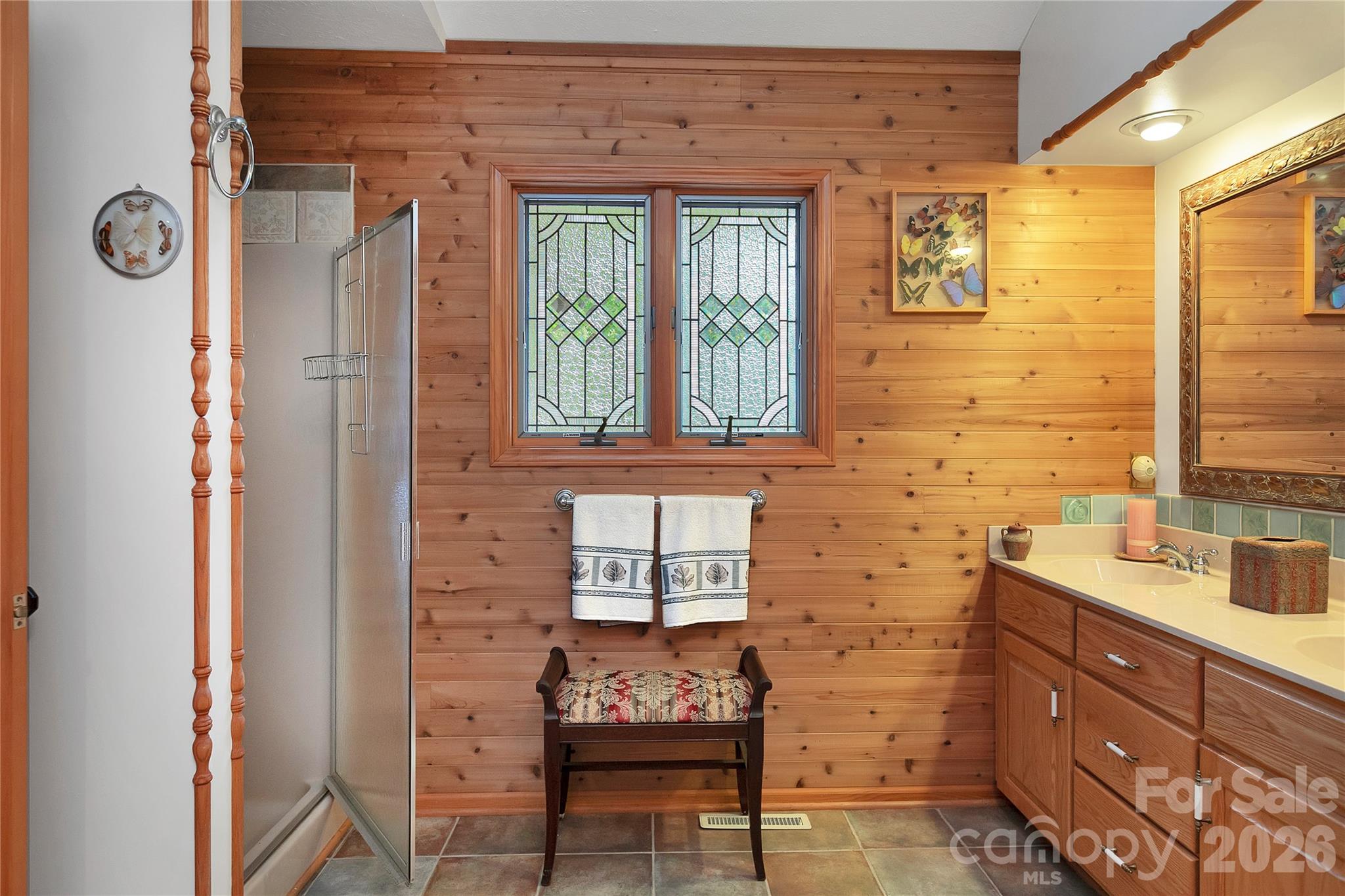 The primary bathroom includes a walk-in shower with its double sink vanity. Stained-glass windows as well. - 275 Hubbard Hollow Road, Rosman