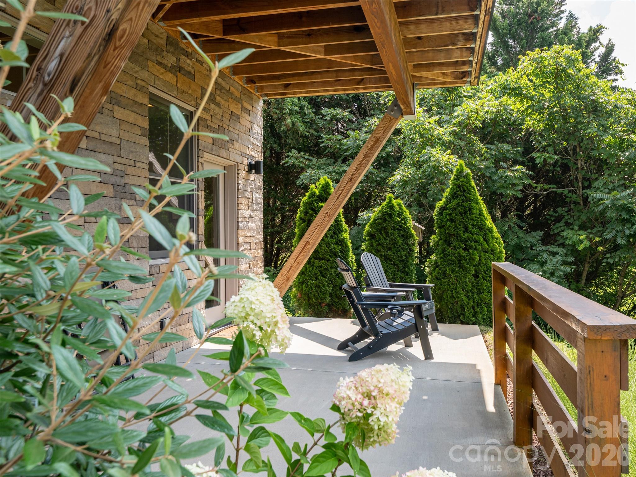 Lower level patio surrounded by lush plants and trees - 309 Ava Lane, Asheville