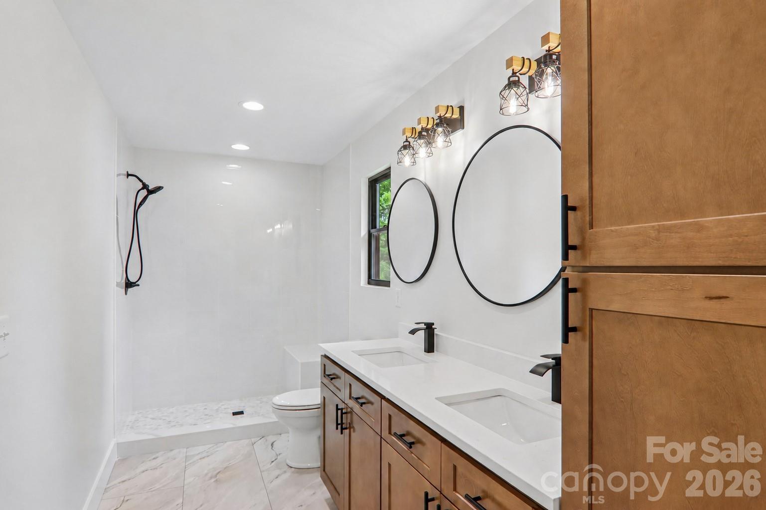 Primary bathroom with double vanities and beautiful walk-in tile shower with bench seat. - 140 N Main Street, Mars Hill