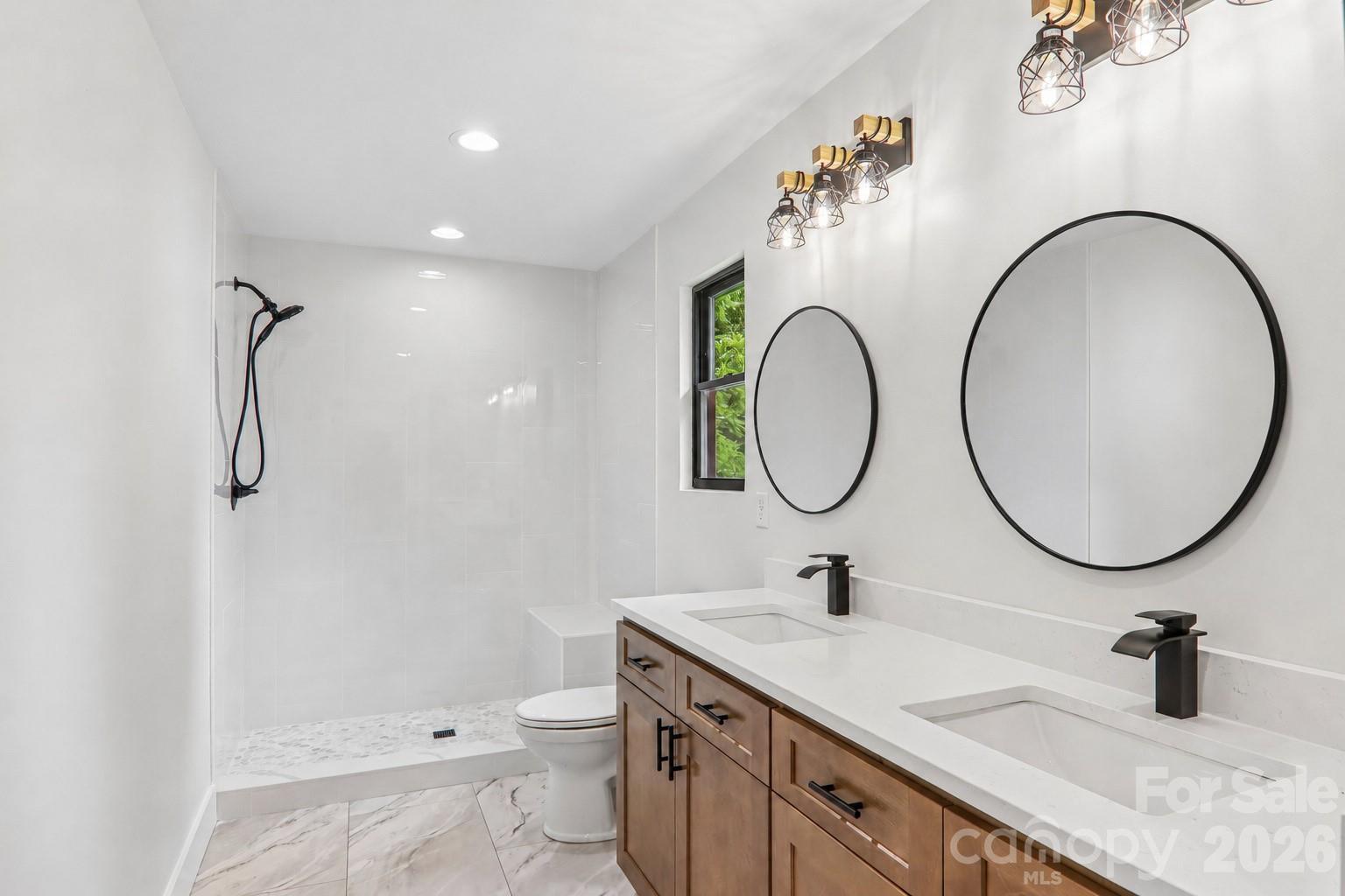 Primary bathroom with double vanities and beautiful walk-in tile shower with bench seat. - 140 N Main Street, Mars Hill