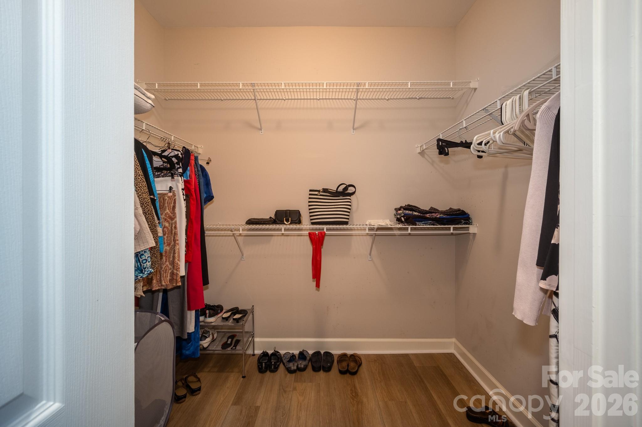 The oversized walk-in closet offers an abundance of storage with wraparound shelving, multiple hanging sections, and convenient space for shoes, handbags, and folded clothing. Its thoughtful layout keeps everything organized while providing plenty of room for seasonal wardrobes and everyday essentials. - 99 Ridgetop Circle, Brevard