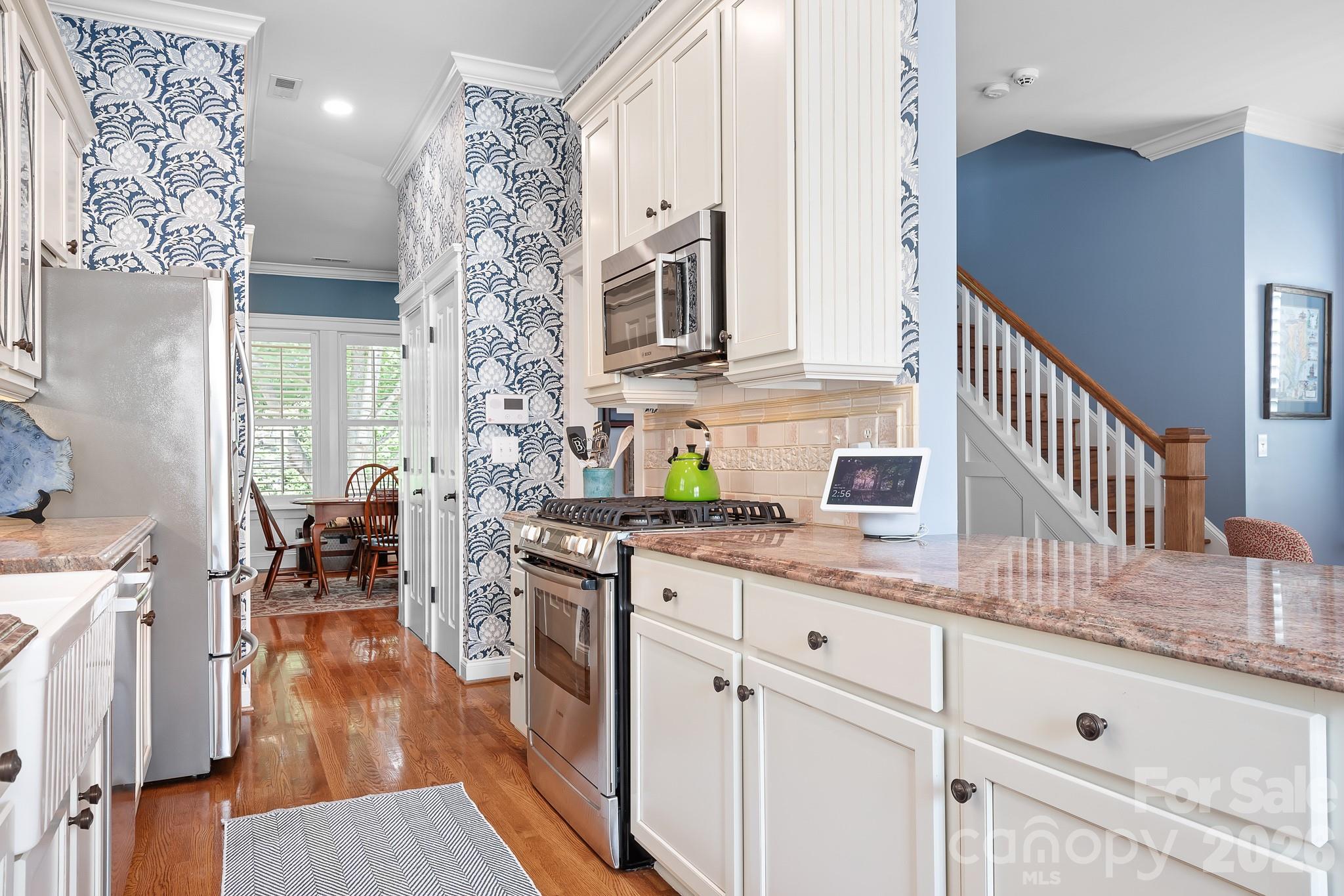 Looking from the breakfast nook into the dining area. Designer tile backsplash, high end granite and Serena and Lily wallpaper with recently replaced cabinets. This kitchen is quietly stunning! - 17525 Calverton Road, Huntersville