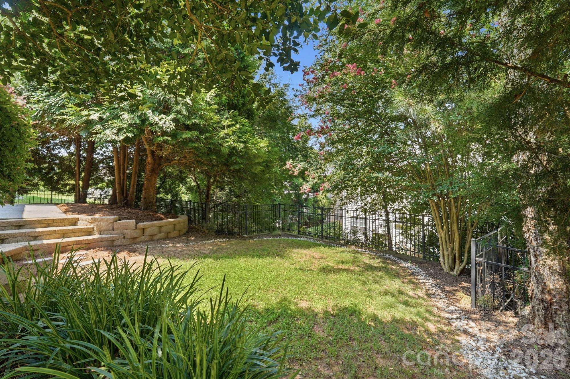 Fenced backyard with retaining wall and lush landscaping - 3016 Connells Point Avenue, Waxhaw