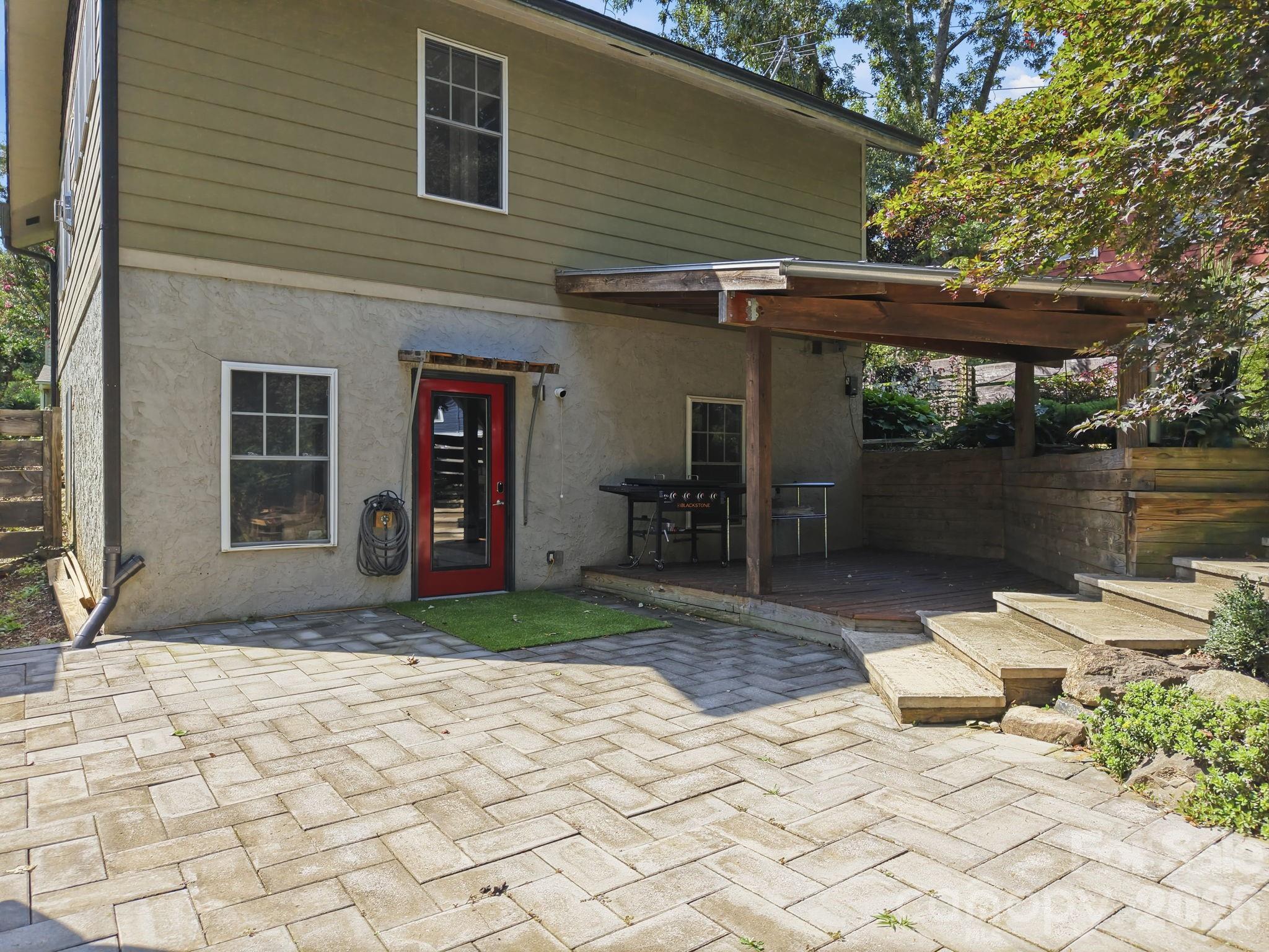 Beautifully landscaped backyard featuring a large paver patio, perfect for outdoor entertaining and relaxation. - 146 Courtland Avenue, Asheville