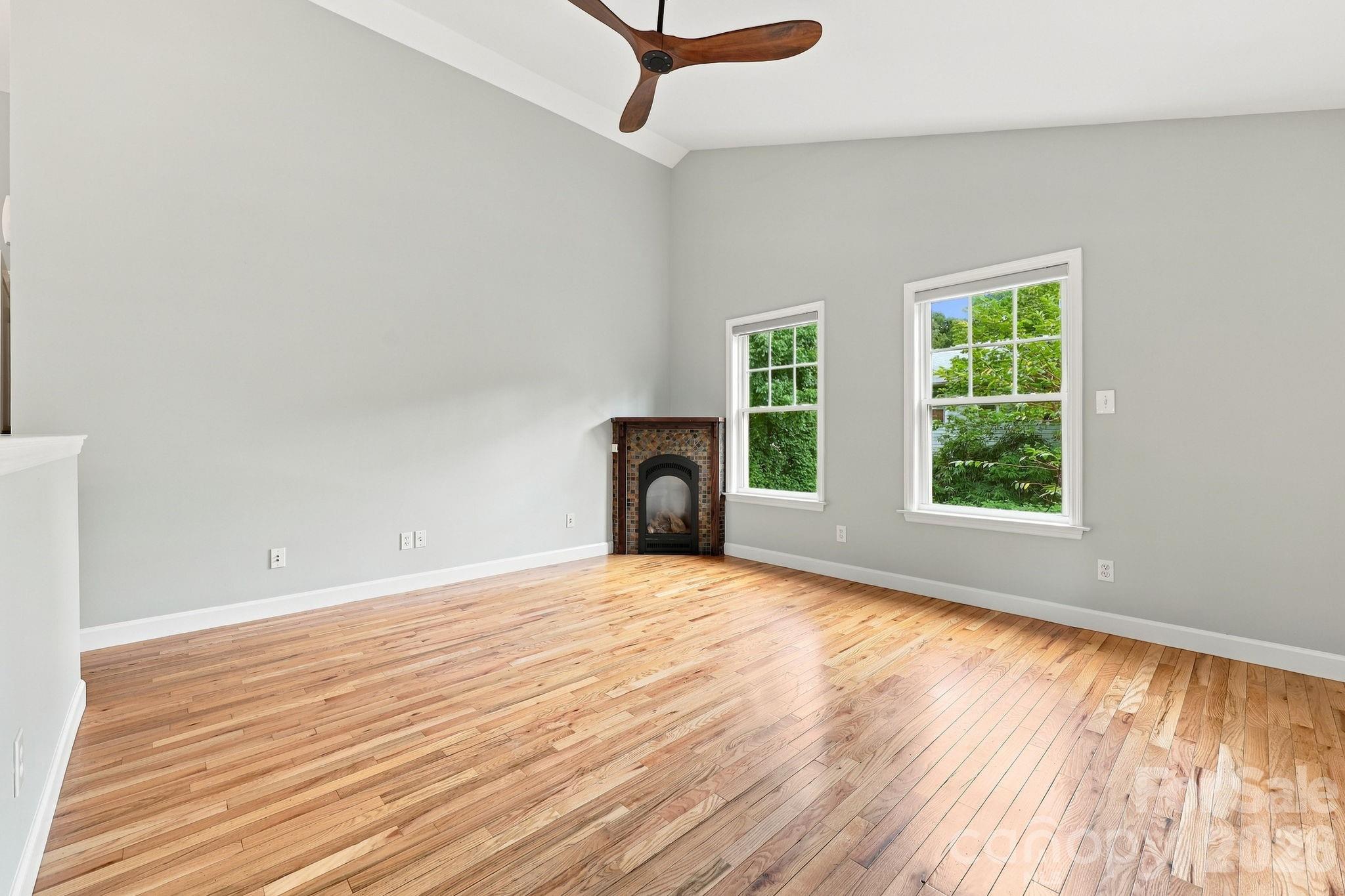 Spacious living room featuring hardwood flooring and a charming vintage-style gas fireplace. - 146 Courtland Avenue, Asheville