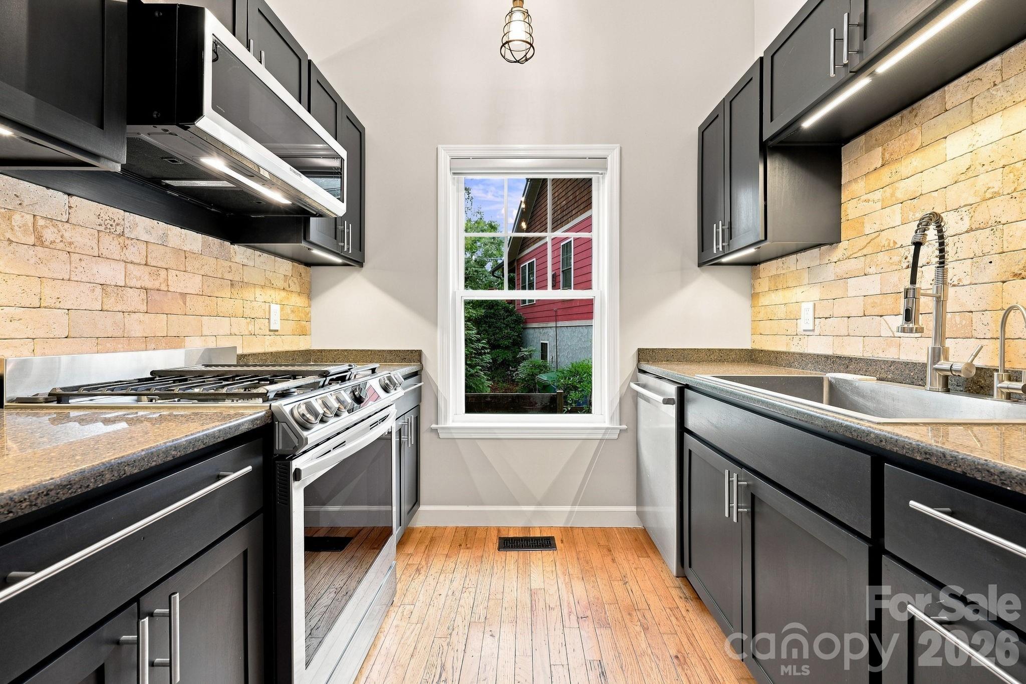 Modern galley kitchen featuring updated stainless steel appliances, and sleek cabinetry. - 146 Courtland Avenue, Asheville