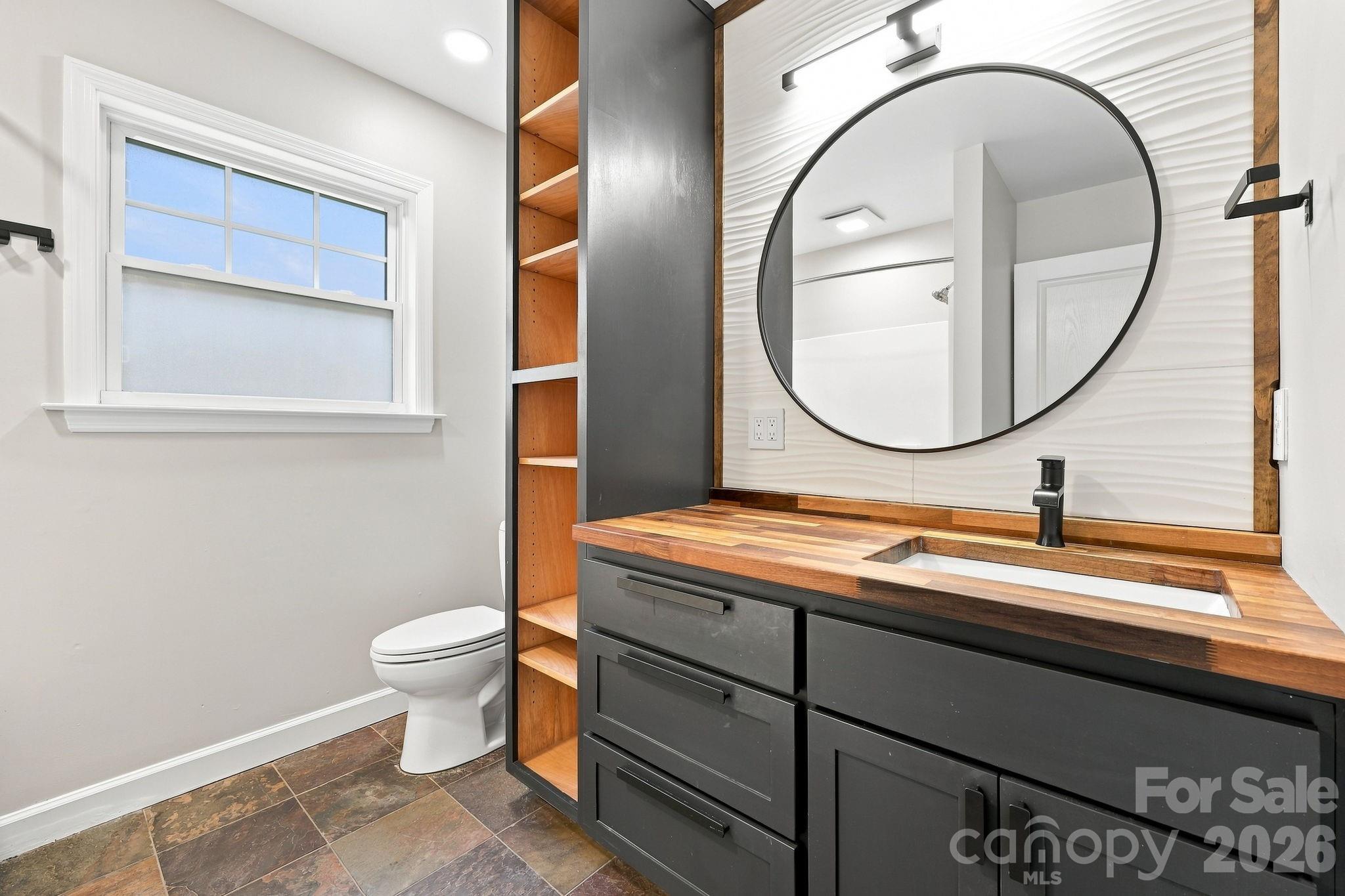Primary bathroom featuring custom shelving and a decorative tile backsplash. - 146 Courtland Avenue, Asheville