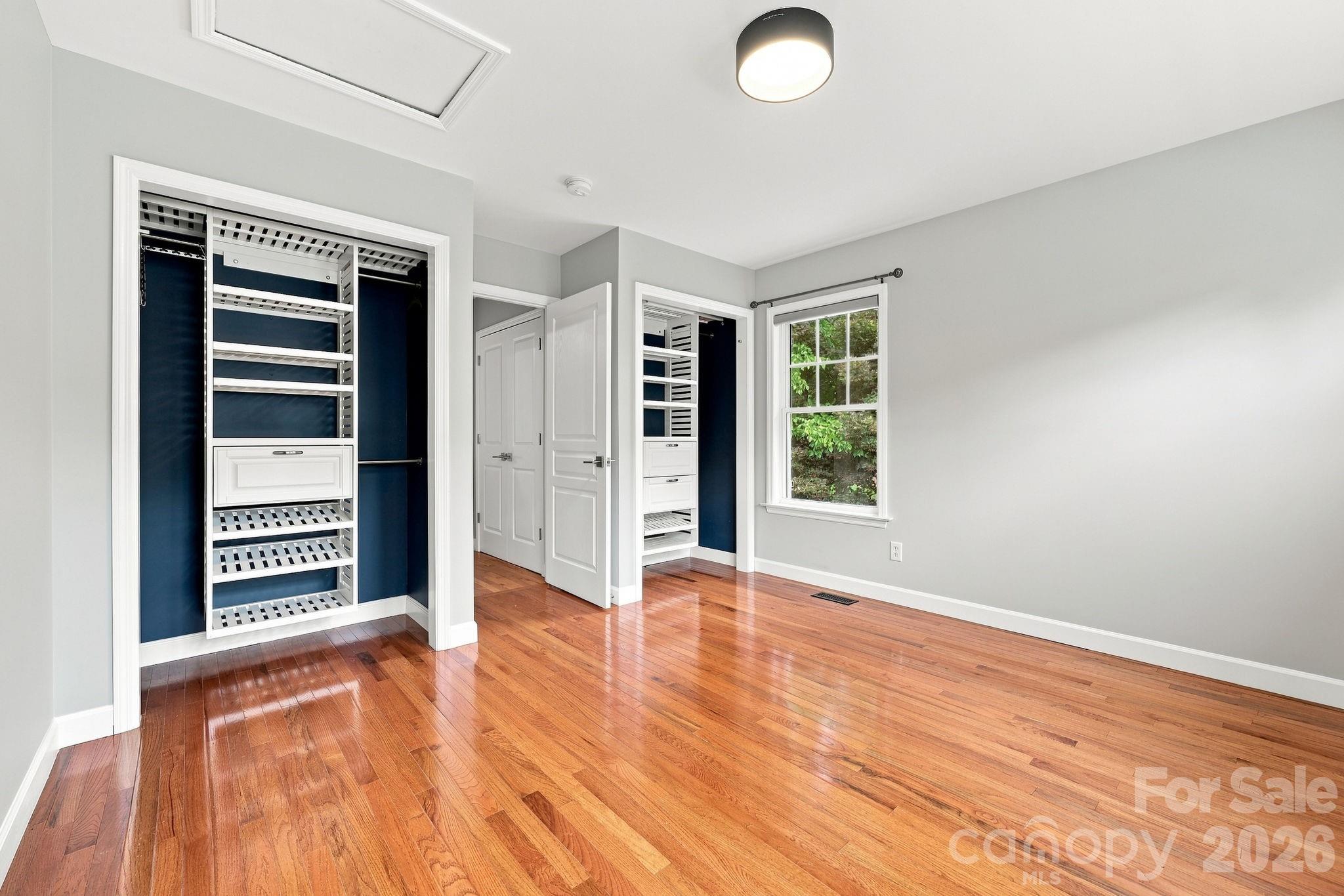 Spacious primary bedroom featuring dual closets equipped with custom organizational systems. - 146 Courtland Avenue, Asheville