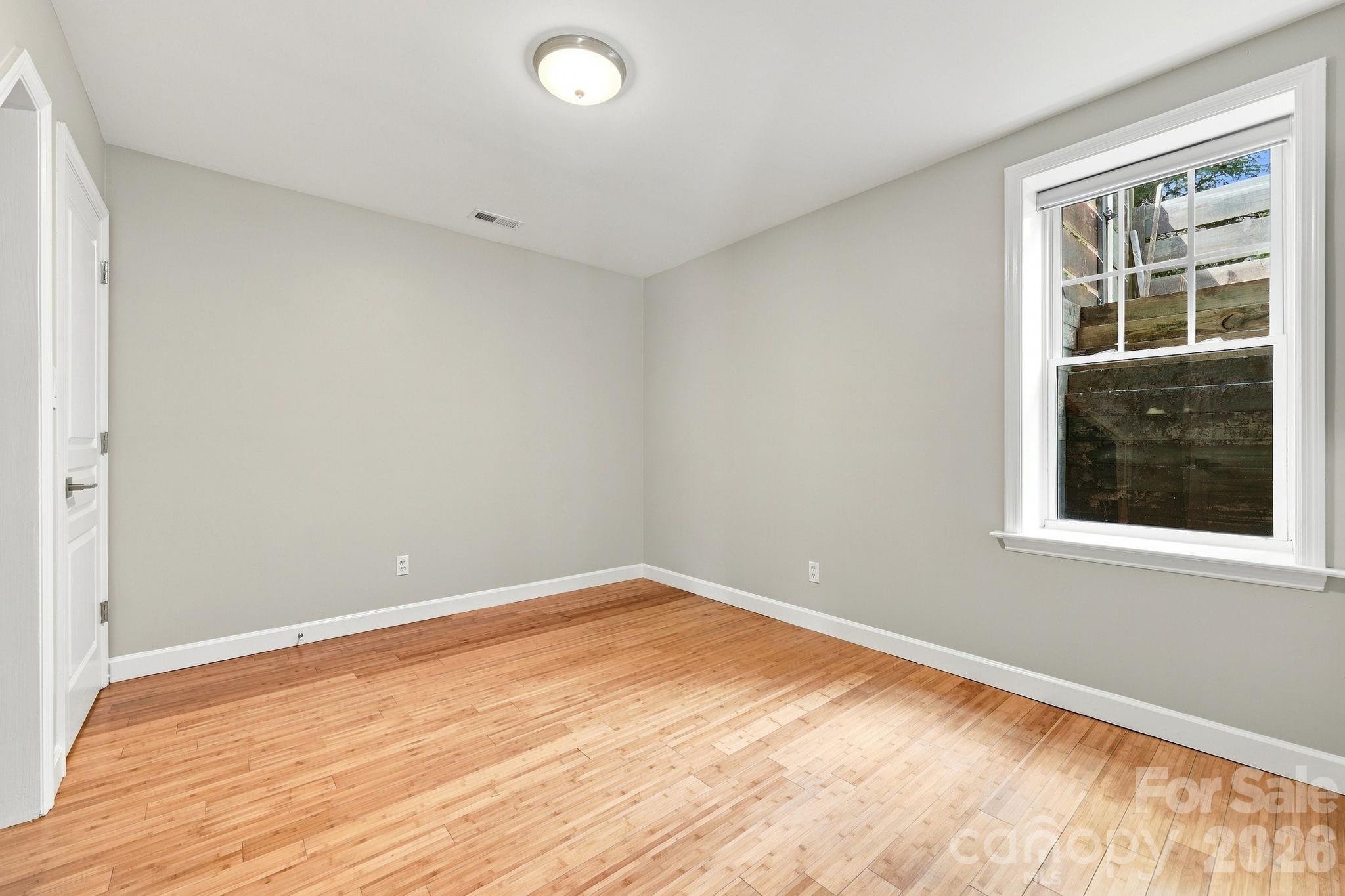 Spacious bedroom located off the family room, featuring a large window that provides plenty of natural light. - 146 Courtland Avenue, Asheville