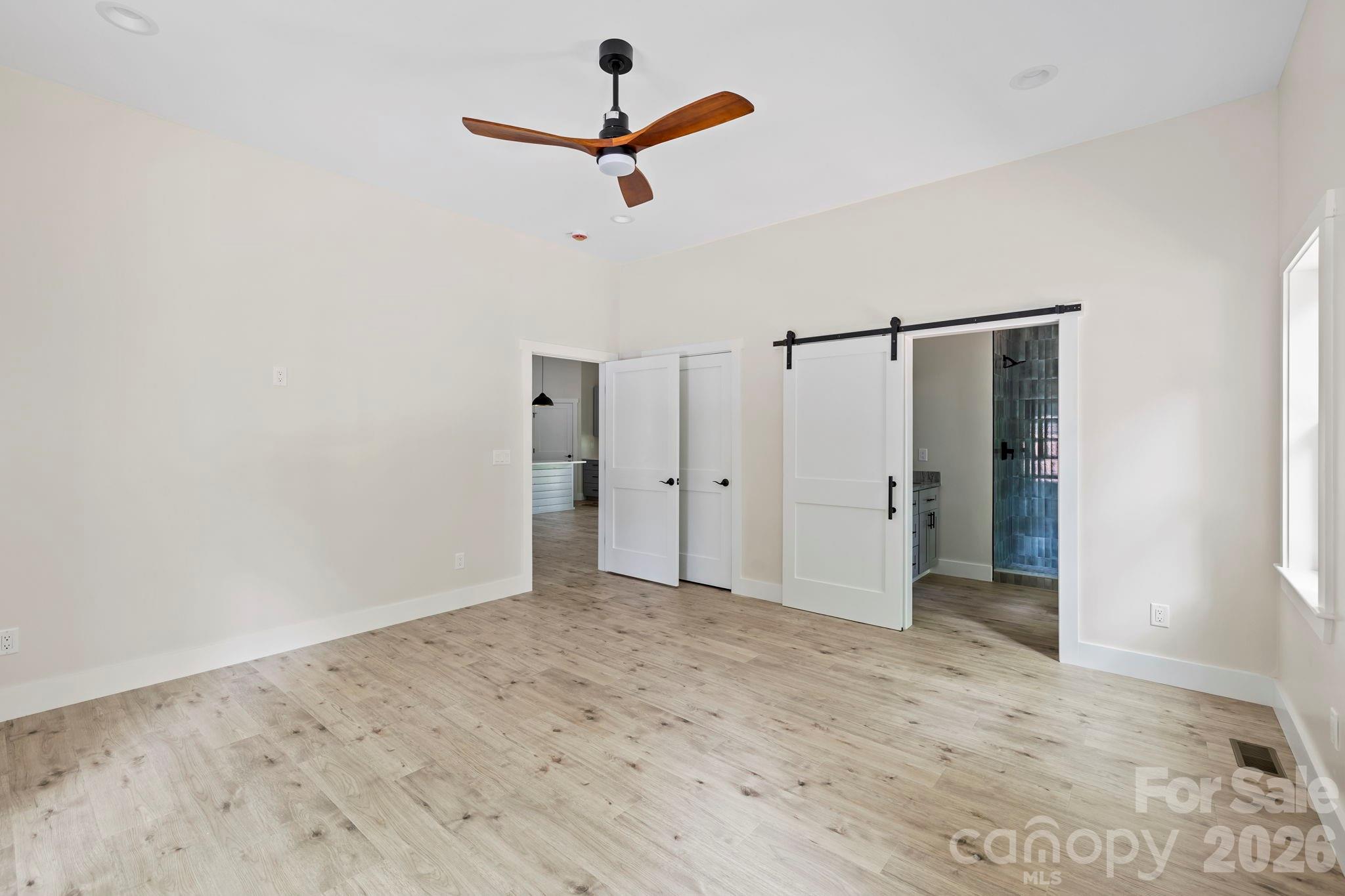 primary bedroom showing barn door for bathroom and closet door - 939 Rocky Mountain Road, Lake Toxaway
