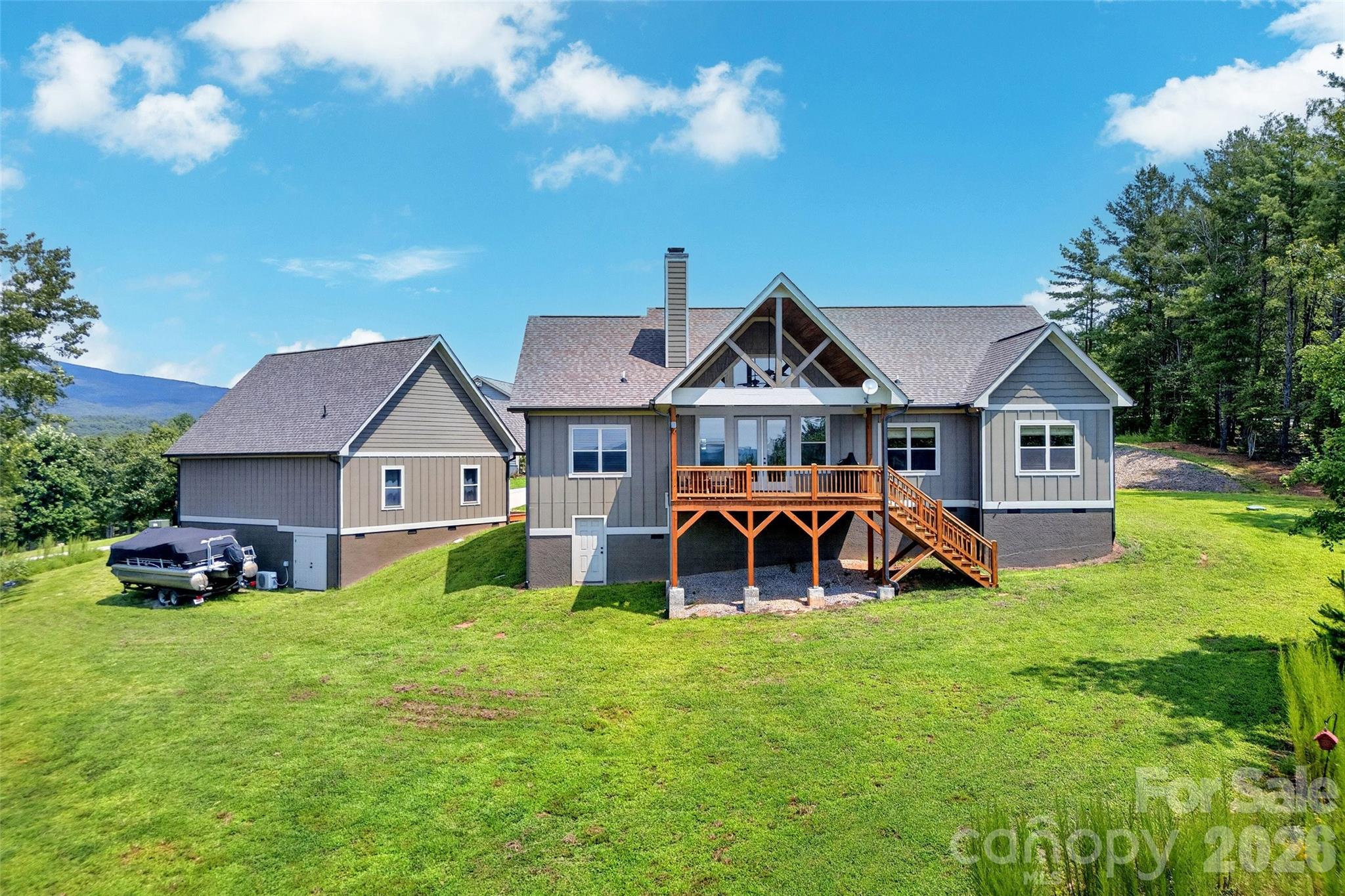 Aerial from the rear: deck, porch, and mountain backdrop on 1.44 acres - 207 Lake Crest Drive, Nebo