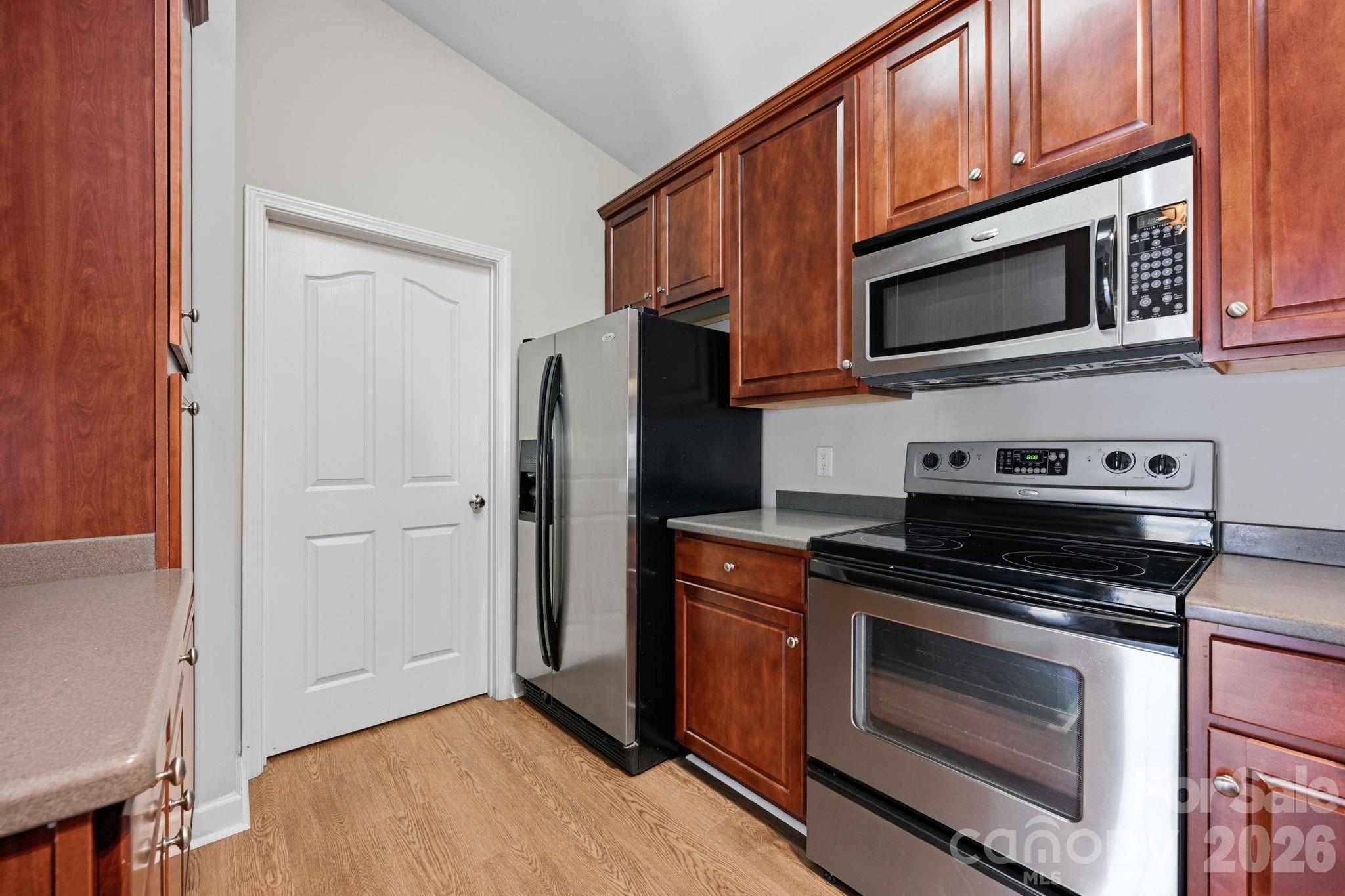 More cabinets and large side by side refrigerator. Door opens to laundry room and storage. - 16648 E Amberside Road, Cornelius