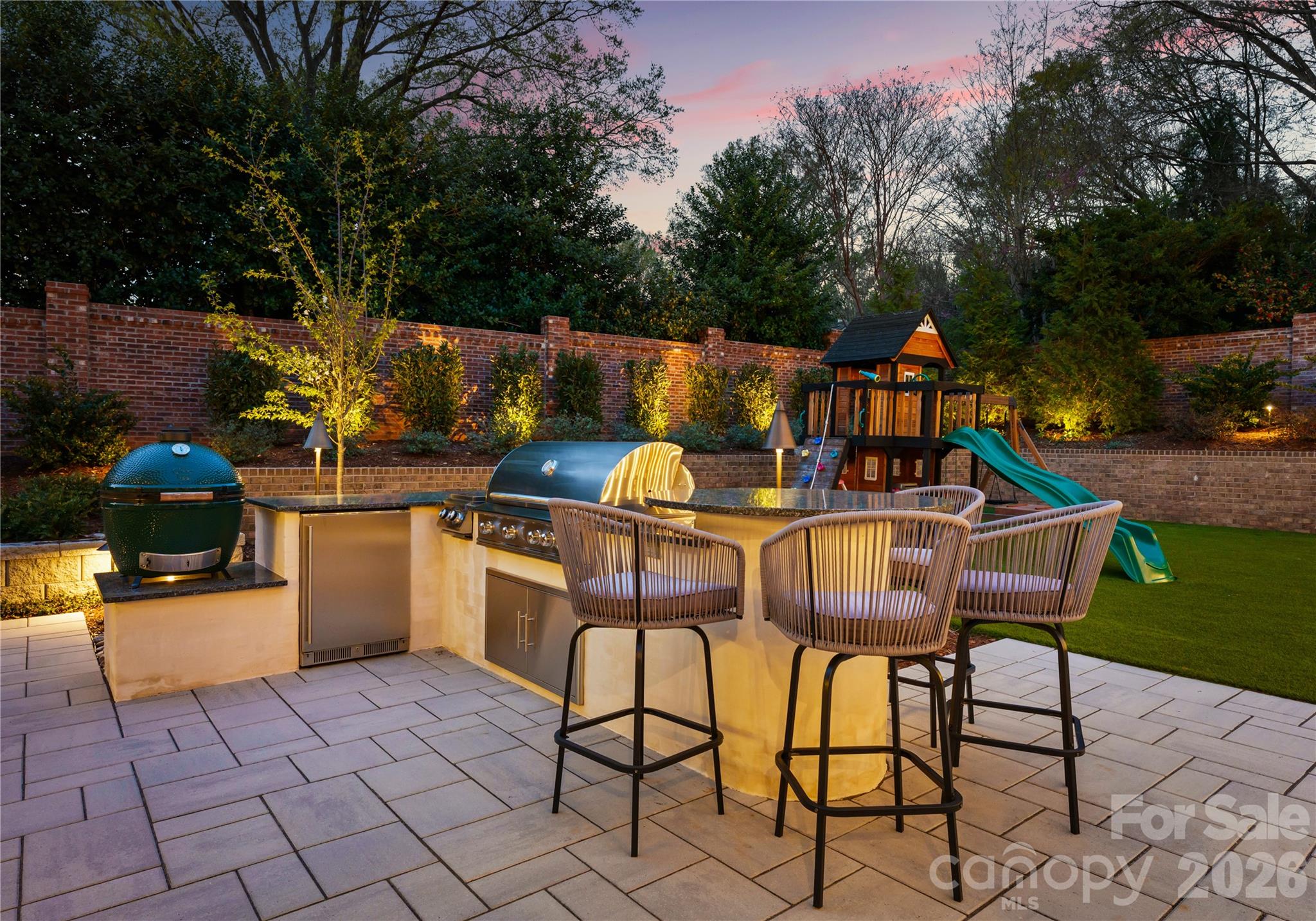 Outdoor kitchen with gas grill, gas cooktop, Big Green Egg, beverage fridge, and bar seating for 4. - 2610 Sedley Road, Charlotte
