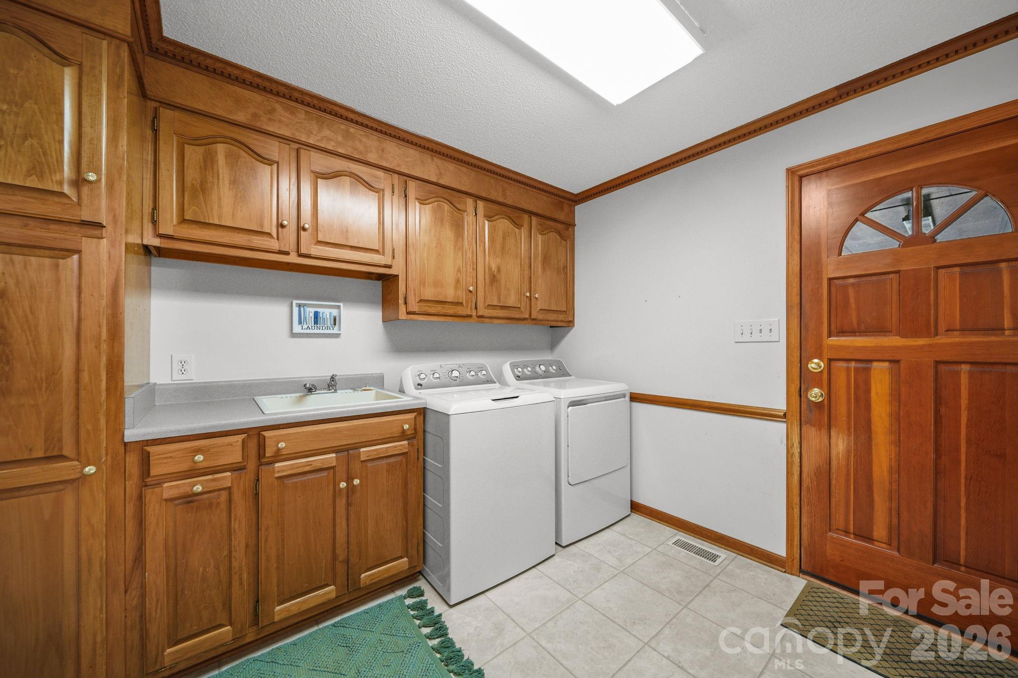 The large laundry room includes cabinetry and a sink. The washer and dryer convey with the property. - 3008 Eaker Drive, Cherryville