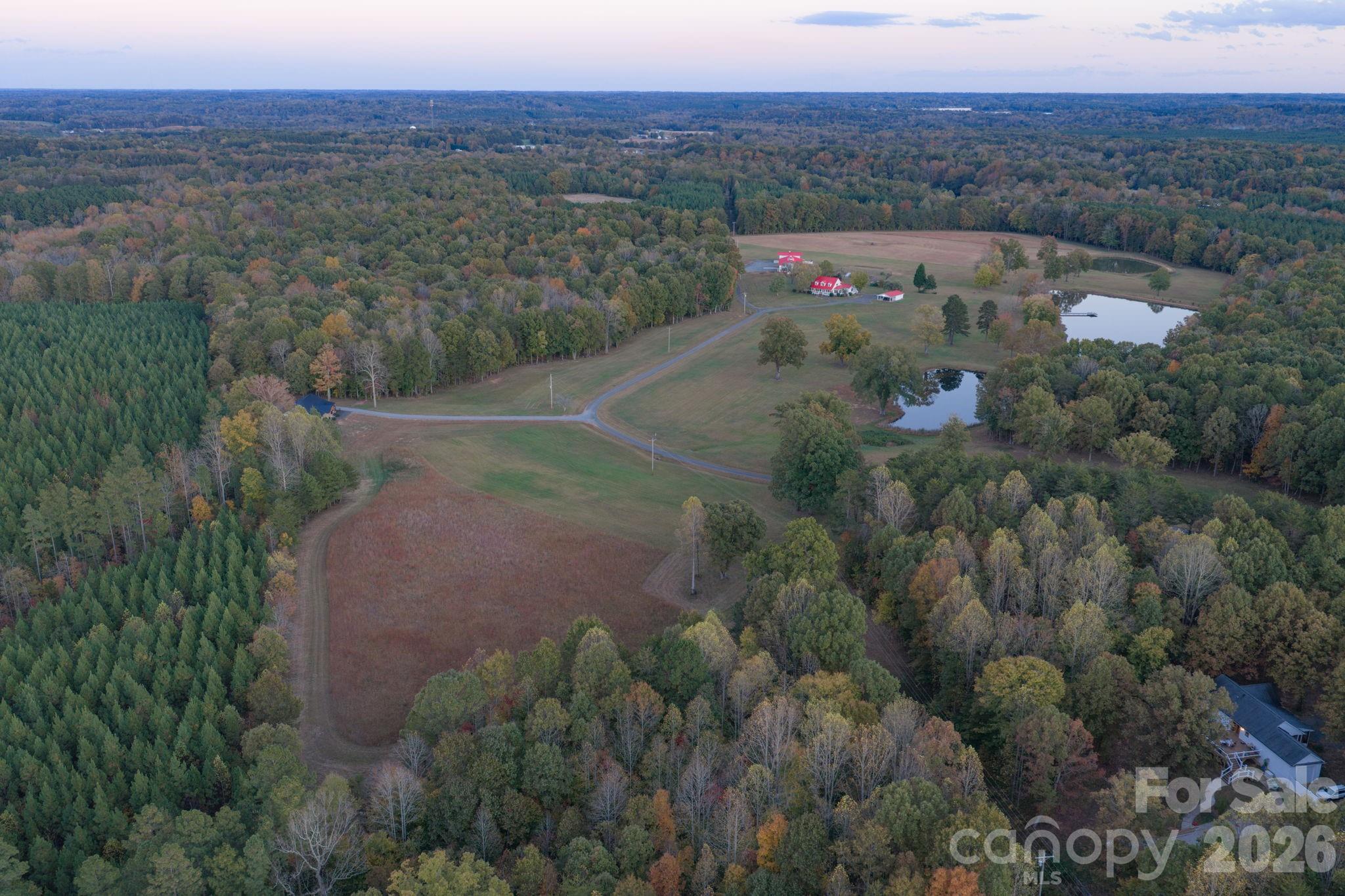 Aerial shot of open pasture land, 3 stocked pond, private driveway, wooded areas, and guest house seclusion from the main farm house. - 1260 Beaver Island Trail Road, Walnut Cove