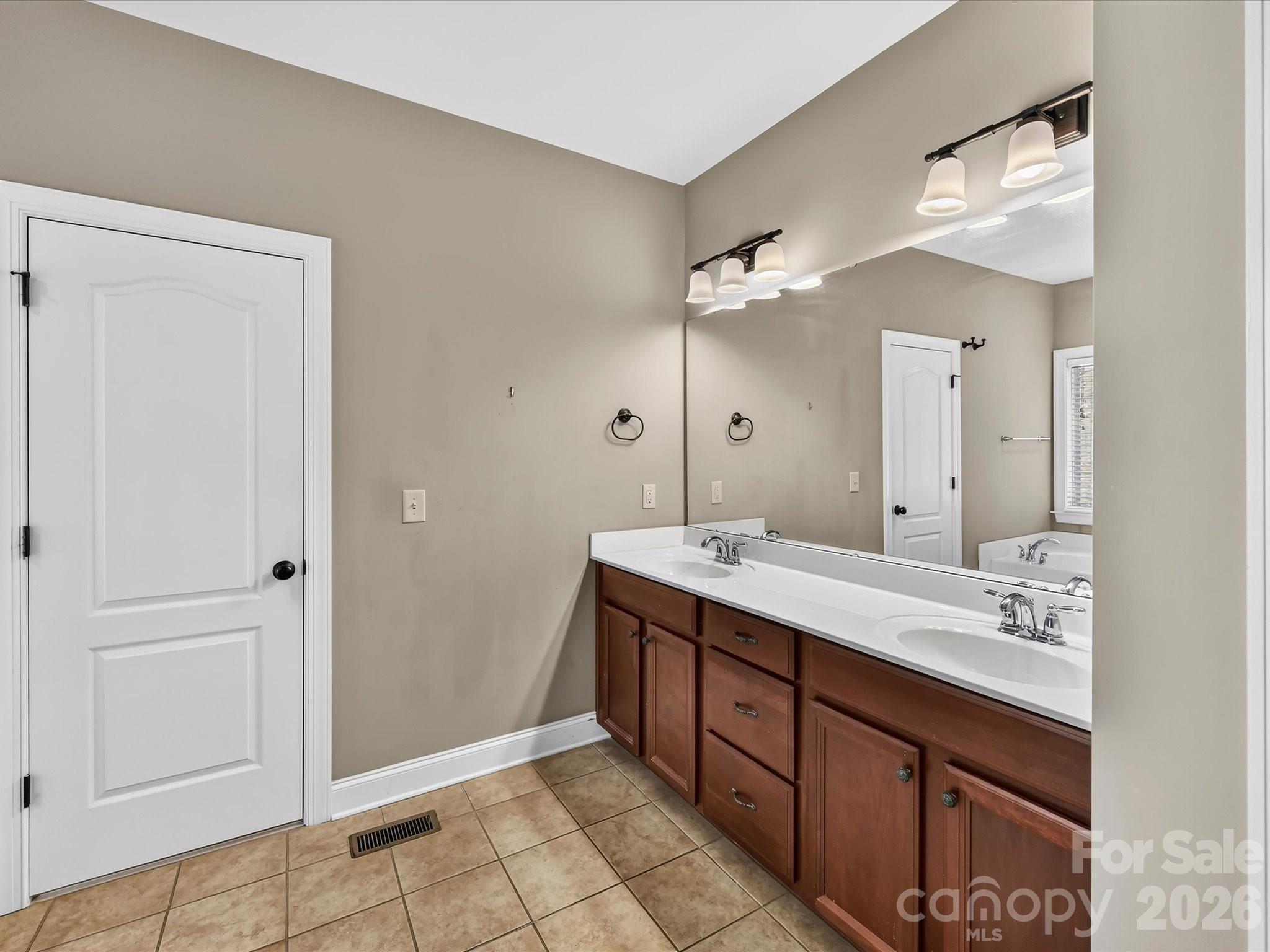 Spacious primary bath features a long dual-sink vanity, generous counter space, and convenient access to the walk-in closet - 11203 Warfield Avenue, Huntersville
