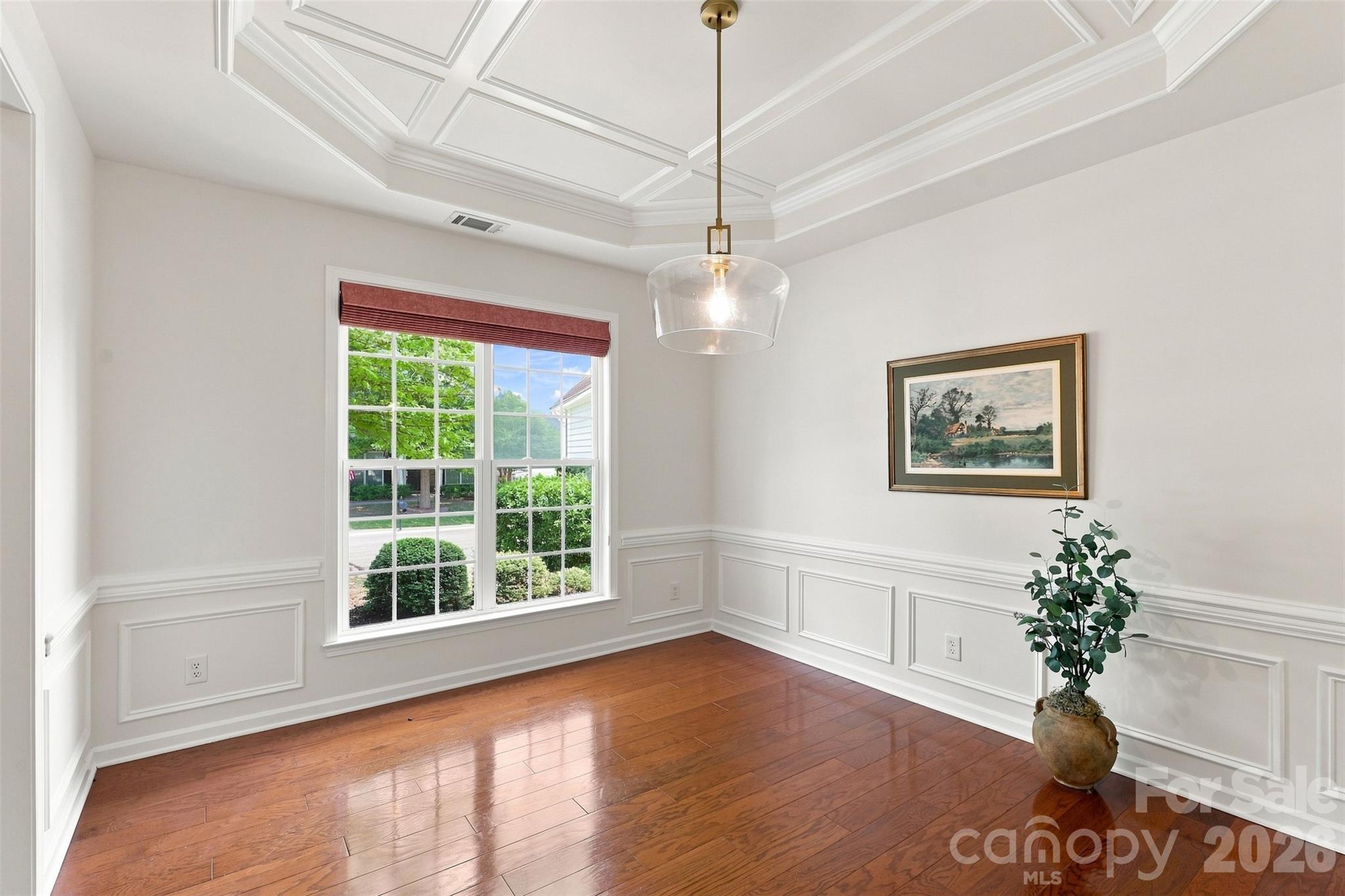 Elegant formal dining room is beautifully finished with a coffered ceiling, wainscoting, and a statement chandelier—an inviting setting for holidays and special gatherings - 10345 Scotland Avenue, Indian Land