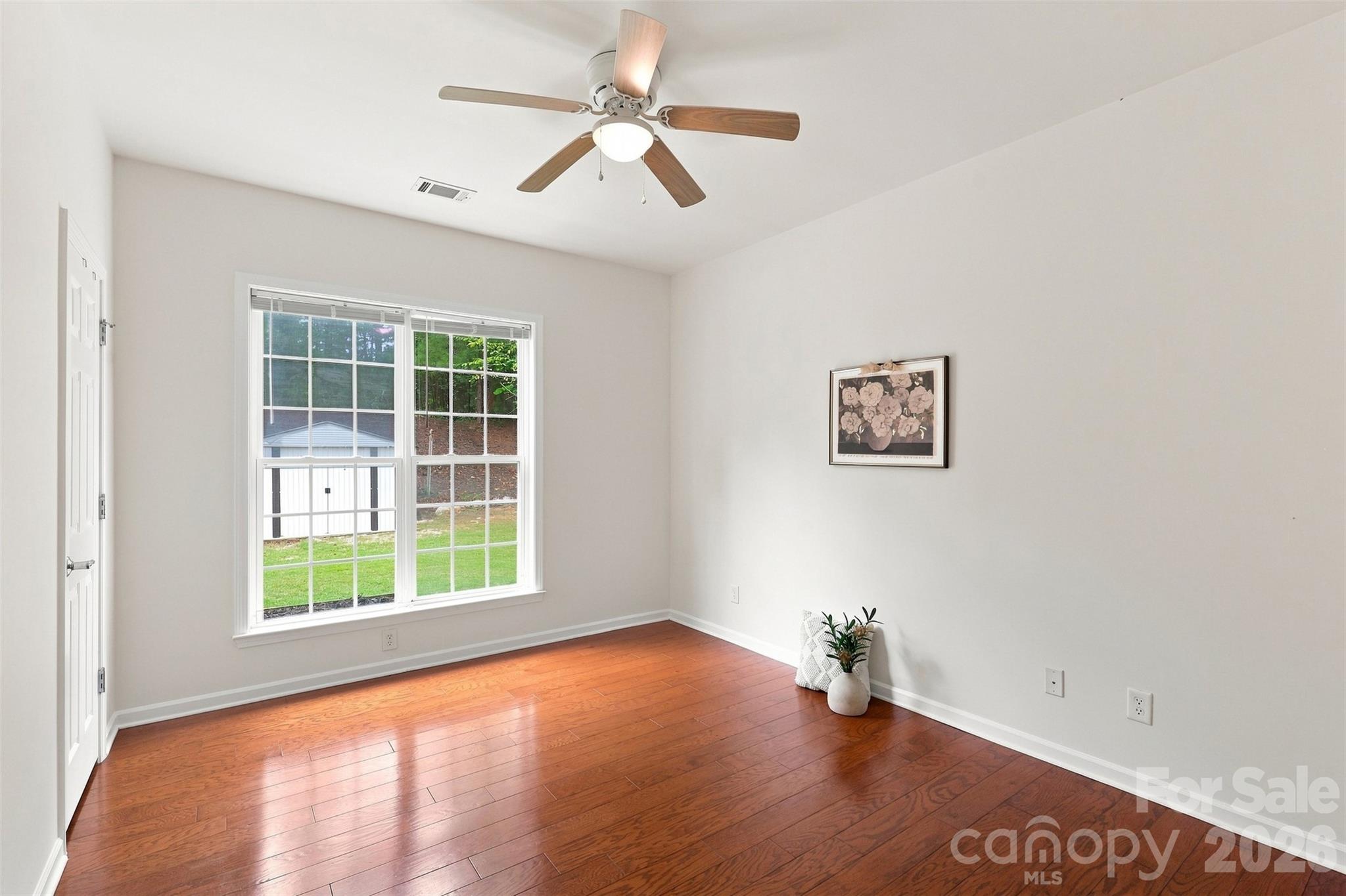 Main-level guest bedroom offers comfortable accommodations with hardwood flooring, a ceiling fan, and convenient access to a nearby full bath - 10345 Scotland Avenue, Indian Land